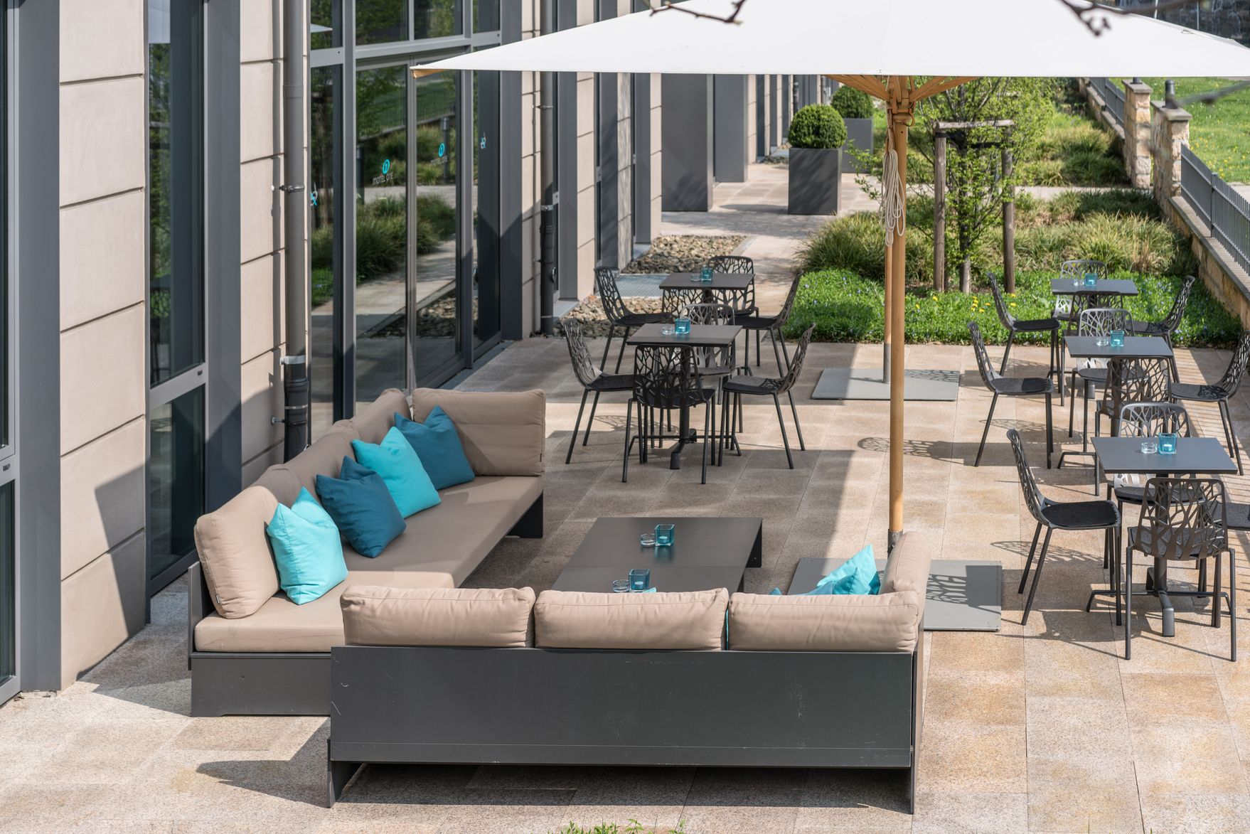 Hotel Dresden Palaisplatz Motel One Aussenbereich mit mehreren Sitzgelegenheiten sowie großem Sonnenschirm