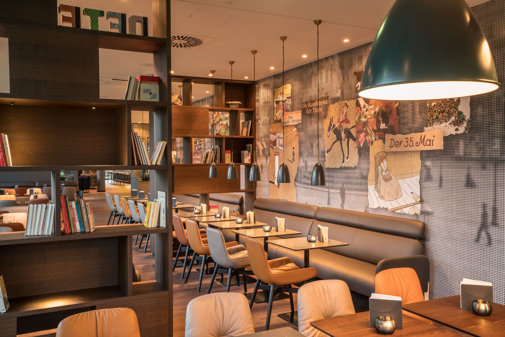 Hotel Dresden Palaisplatz Motel One heller Raum mit mehreren Tischen und Stühlen sowie großen offenen Regalen mit Büchern