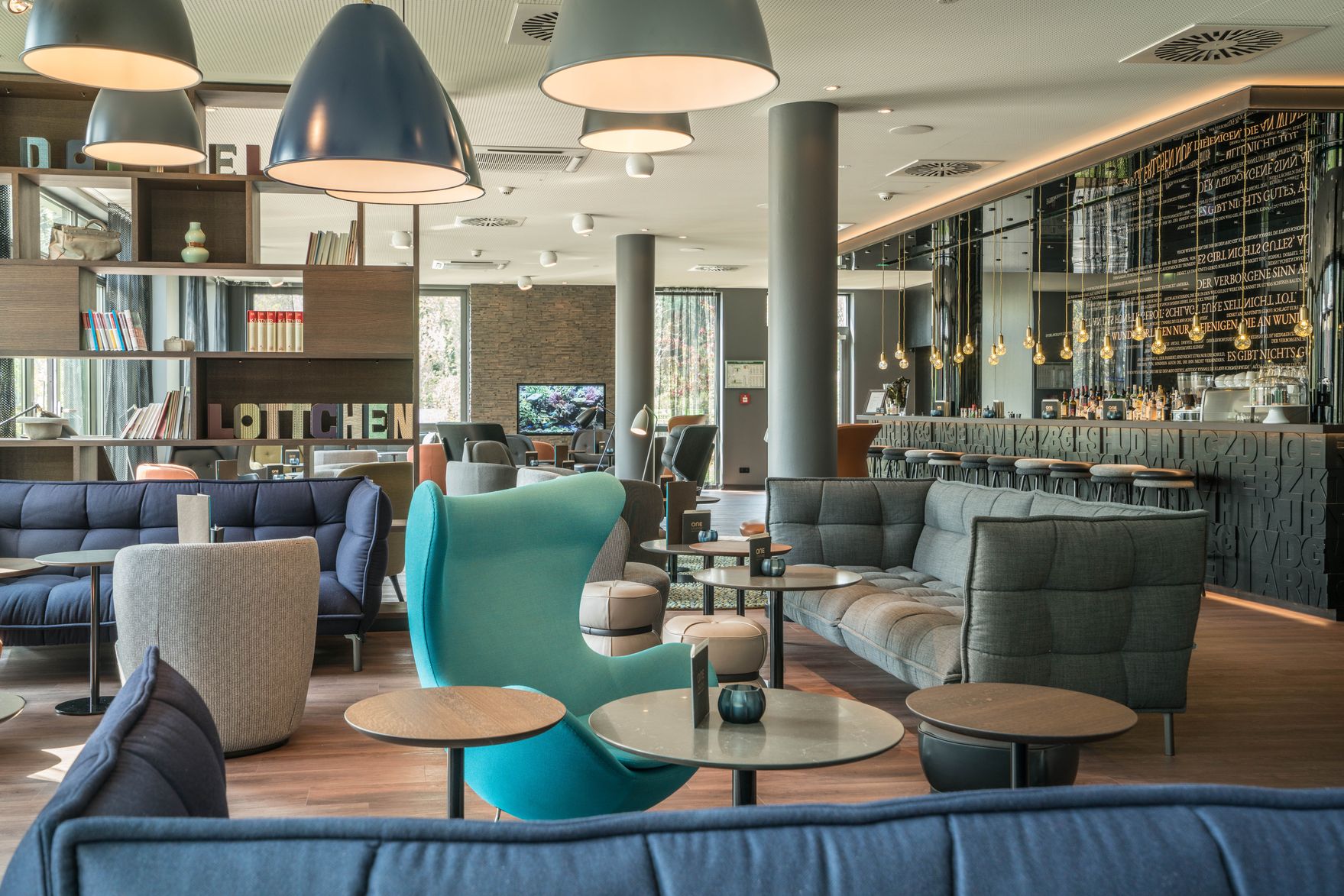 Hotel Dresden Palaisplatz Motel One lichtdurchflutete Lounge sowie Bar mit mehreren Sesseln und Sofas