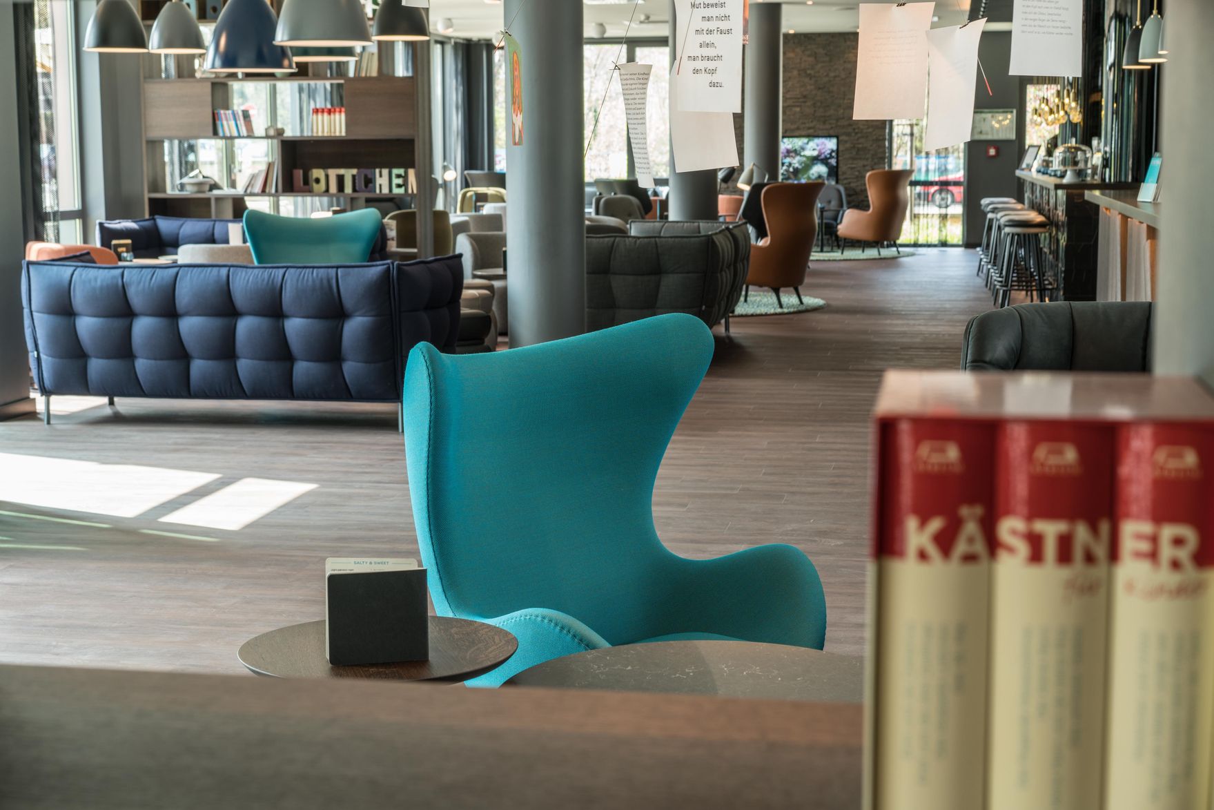 Designhotel Dresden Palaisplatz Motel One lichtdurchflutete Lounge mit mehreren Sitzgelegenheiten sowie Bar im Hintergrund