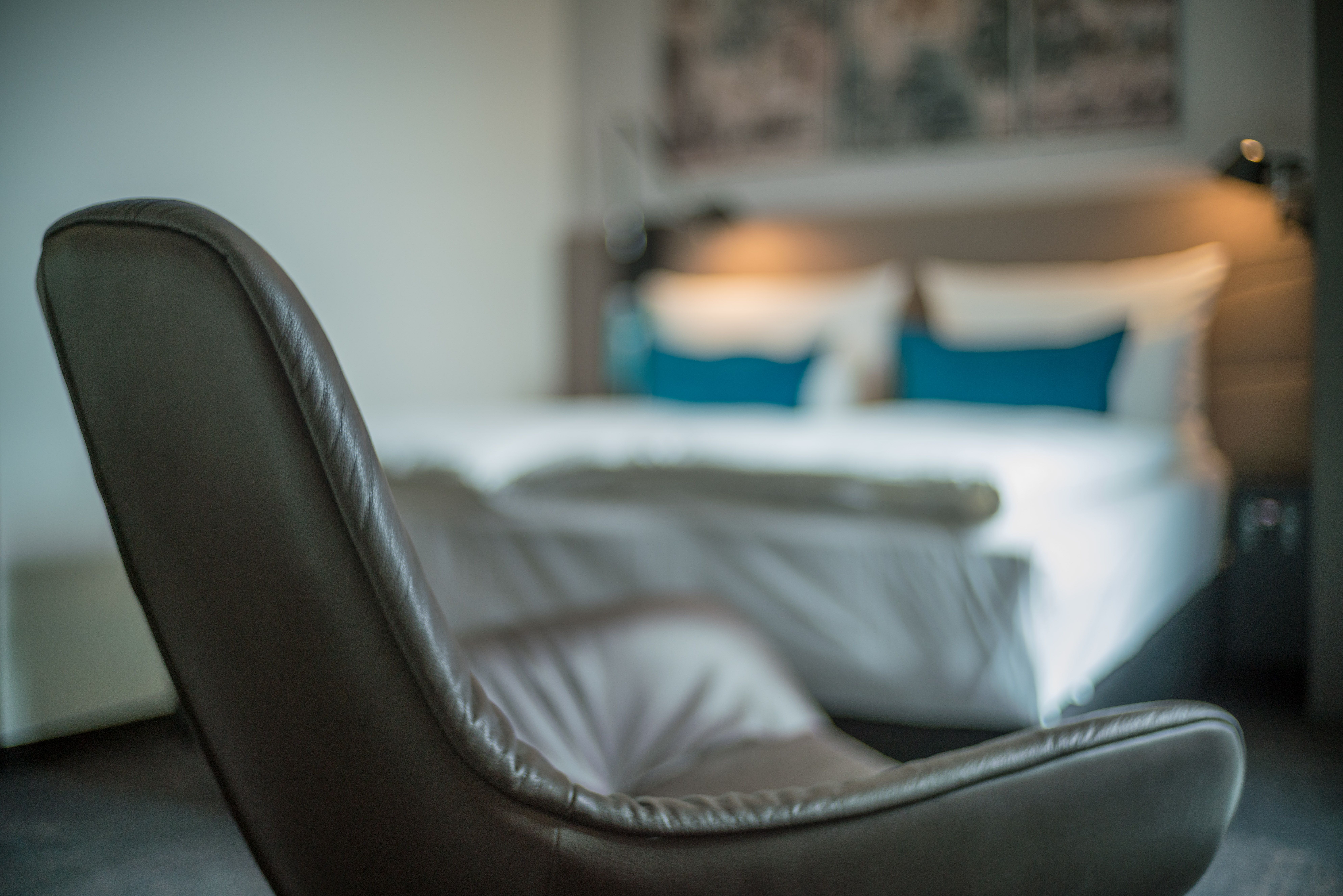 designhotel Dresden Palaisplatz Motel One room with focus on an armchair, double bed in the background