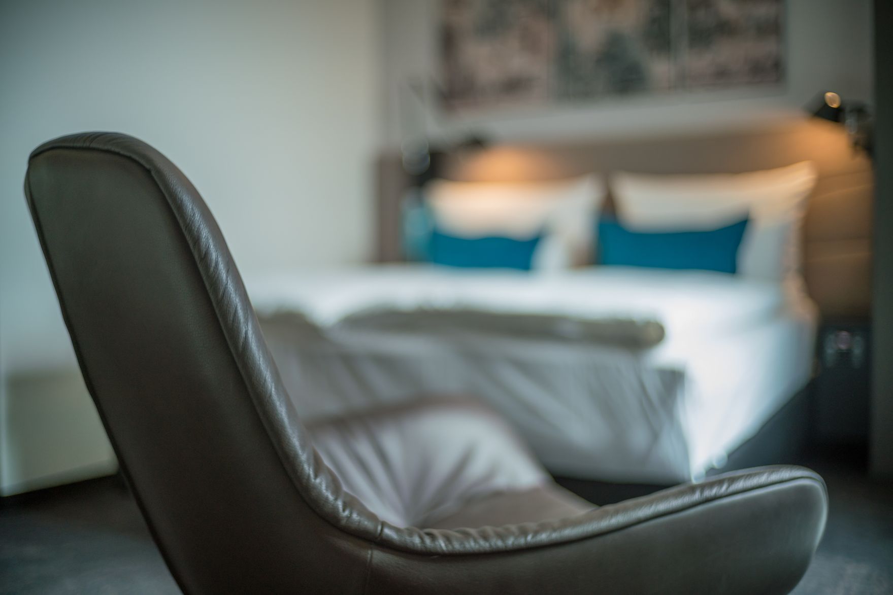 Designhotel Dresden Palaisplatz Motel One Zimmer mit Fokus auf einen Sessel, im Hintergrund ein Doppelbett