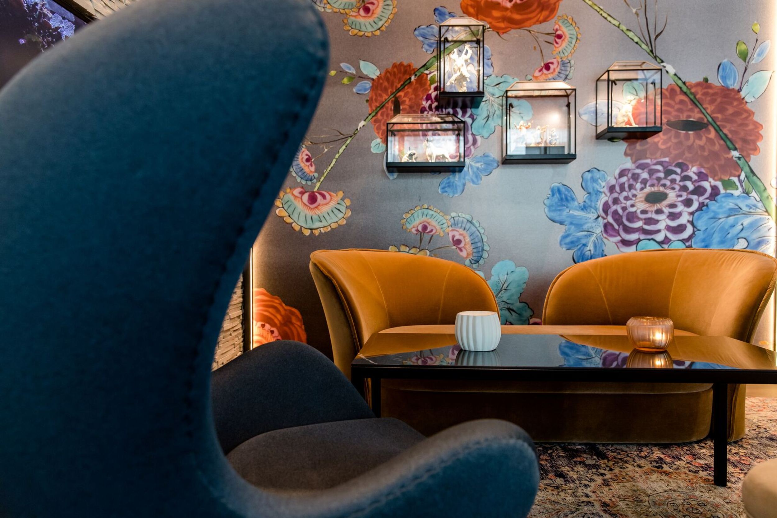 hotel Dresden am Zwinger Motel One lounge with view of egg chair and two additional armchairs in front of floral pattern wallpaper