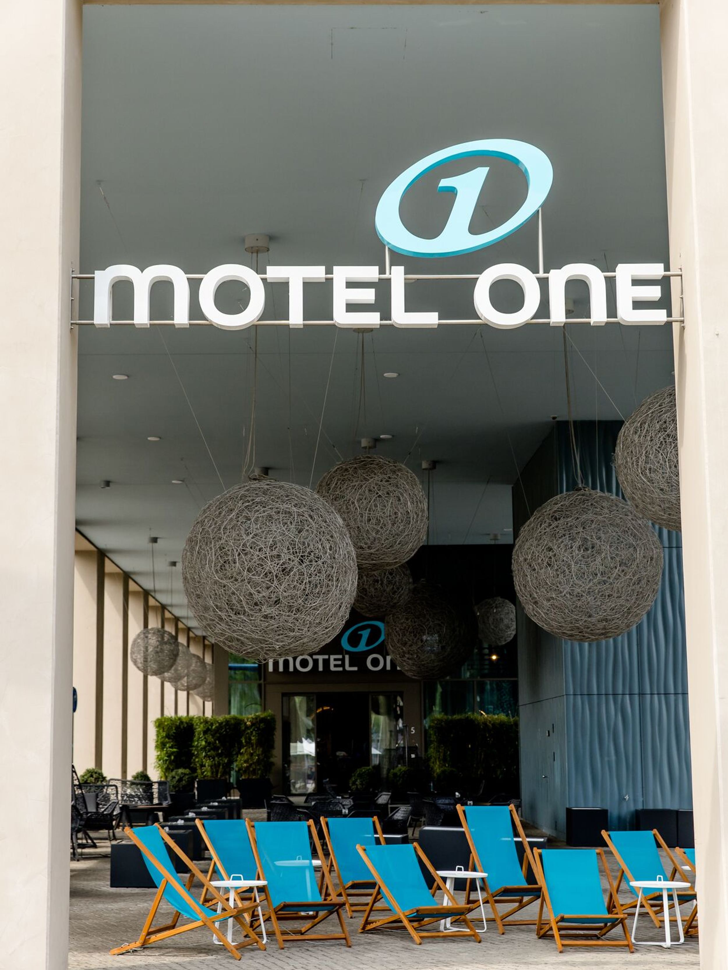 hotel Dresden am Zwinger Motel One entrance area from the outside with large logo and several deck chairs