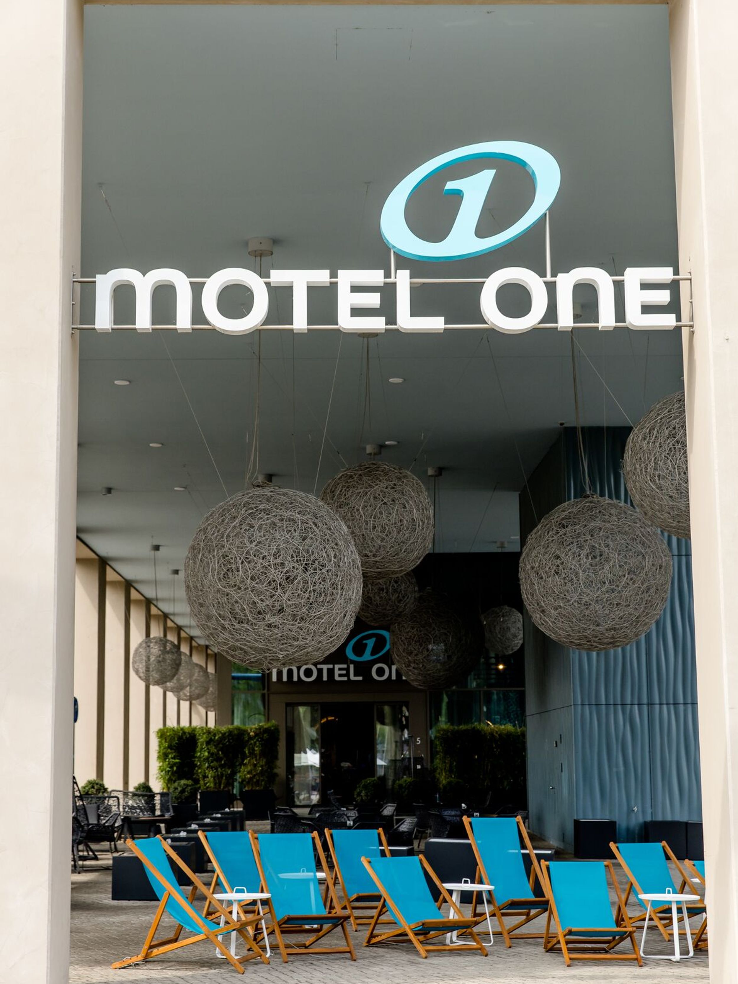 Hotel Dresden am Zwinger Motel One Eingangsbereich von außen mit großem Logo sowie mehreren Liegestühlen