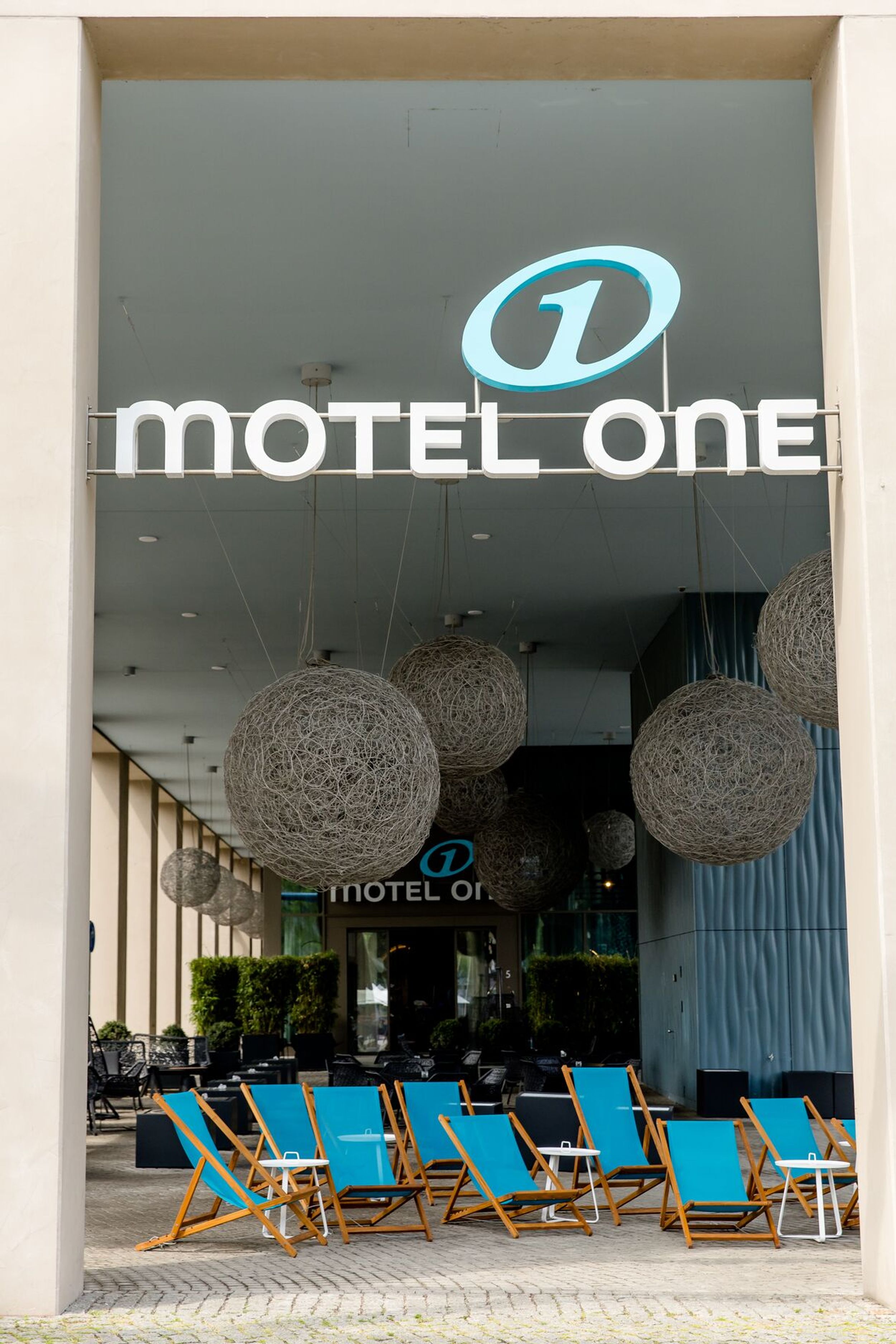 Hotel Dresden am Zwinger Motel One Eingangsbereich von außen mit großem Logo sowie mehreren Liegestühlen