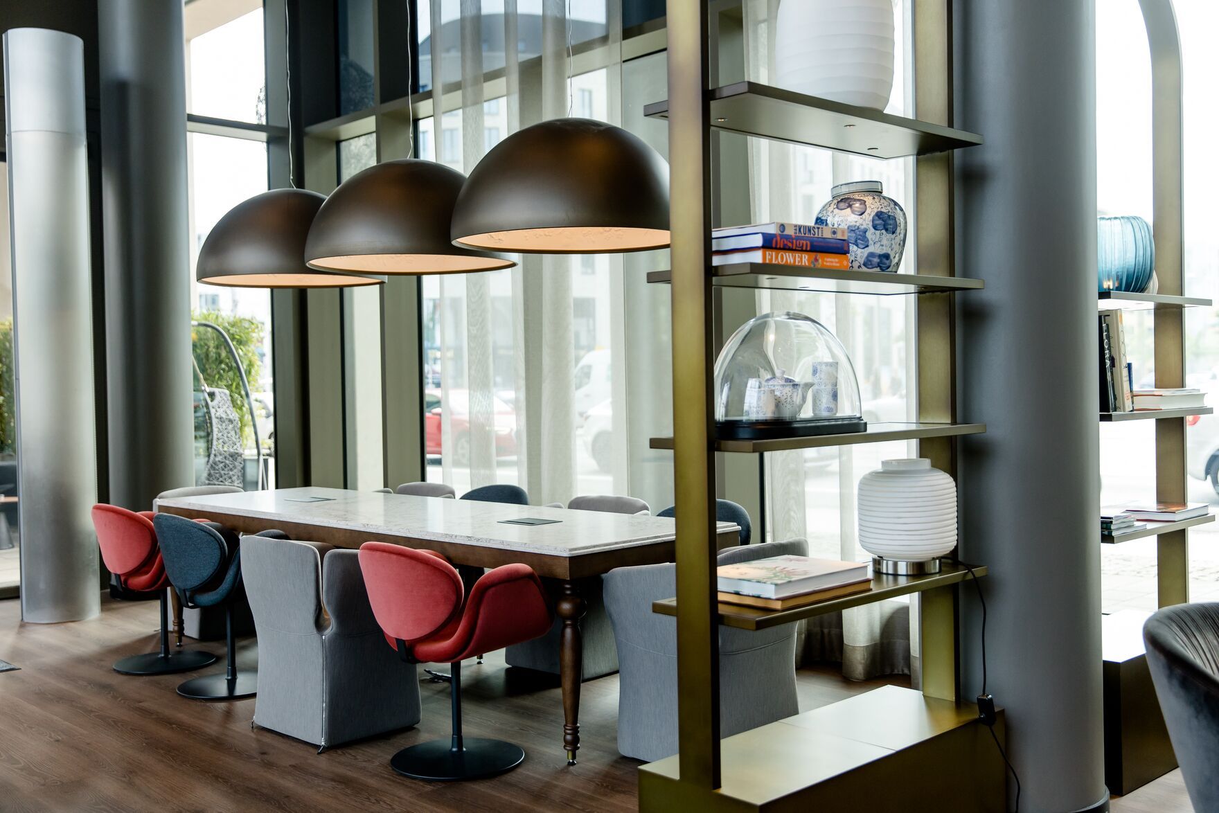 Hotel Dresden am Zwinger Motel One helle Lounge mit bodentiefen Fenstern sowie langer Tisch und mehrere Stühle 