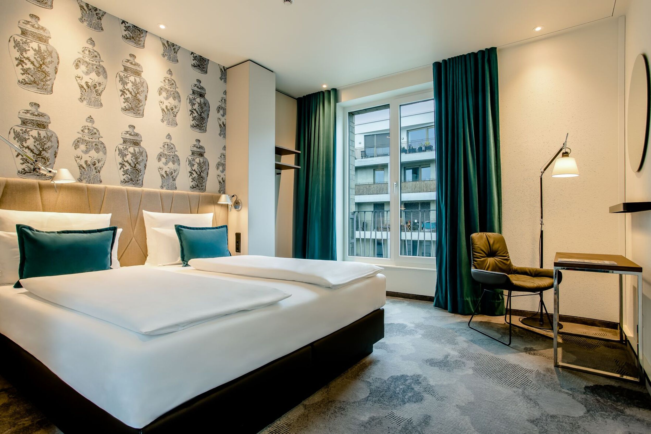 Hotel Dresden am Zwinger Motel One geräumiges Doppelzimmer mit großem Bett, Schreibtisch und Stuhl sowie bodentiefem Fenster