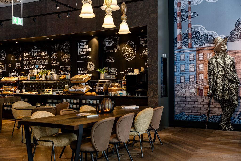 Hotel Dublin Motel One Frühstücksraum mit Tischen und Buffet im Hintergrund