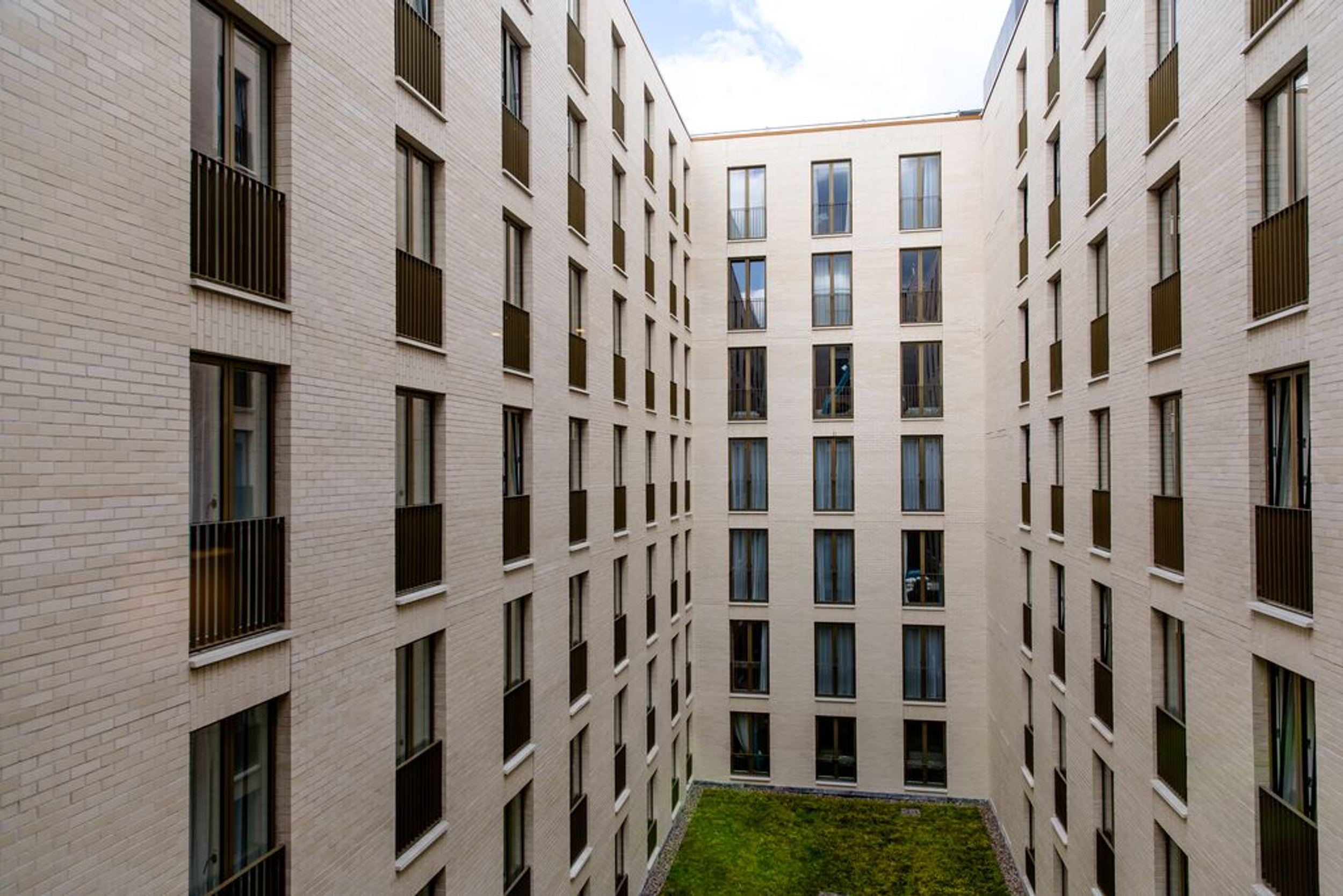 Designhotel Dublin Motel One Blick auf die Fassade mit Blick in den Innenhof mit grünem Rasen