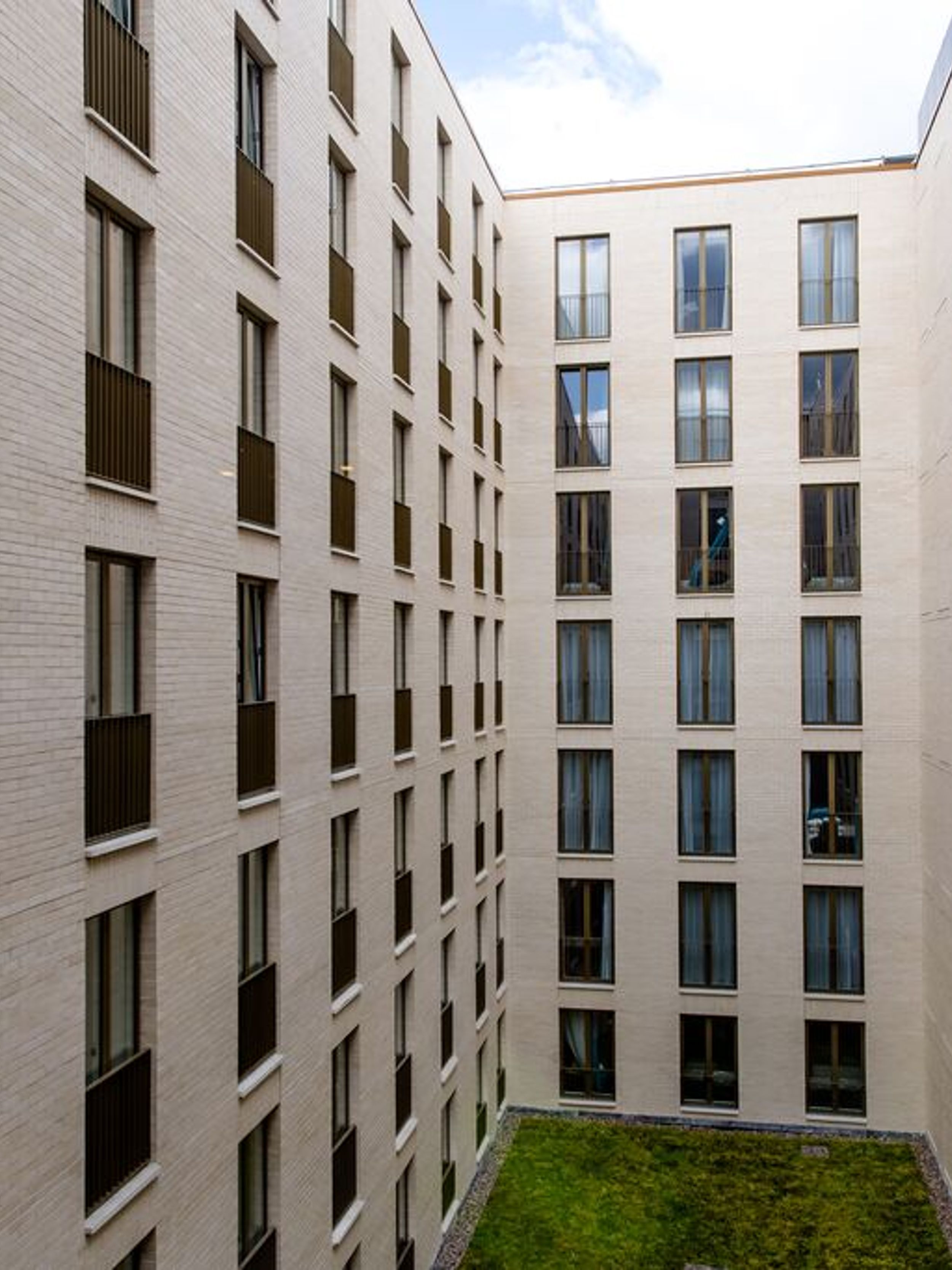 designhotel Dublin Motel One View of the facade with a view of the inner courtyard with green lawn