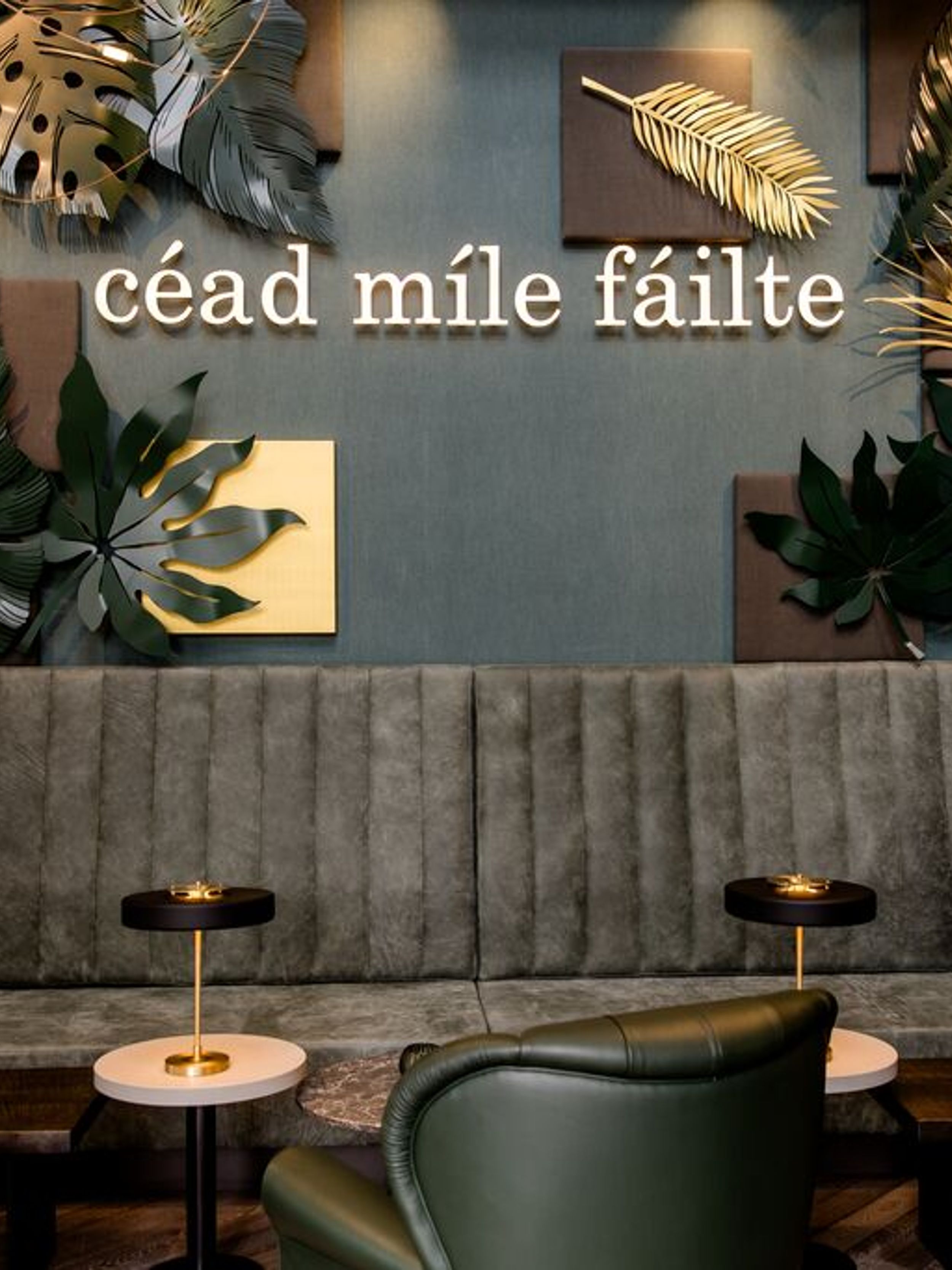 hotel Dublin Motel One lounge with seating and lettering, as well as large leaves as decoration on the wall