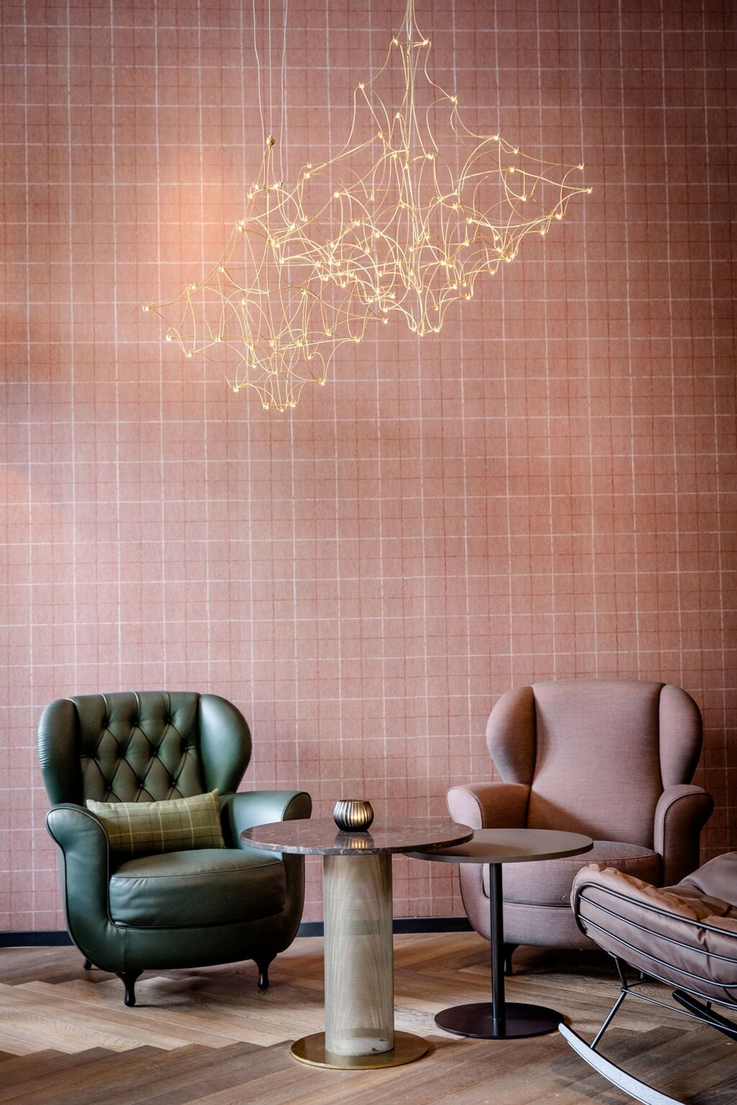 hotel Dublin Motel One two armchairs with side tables in front of large wall in pink