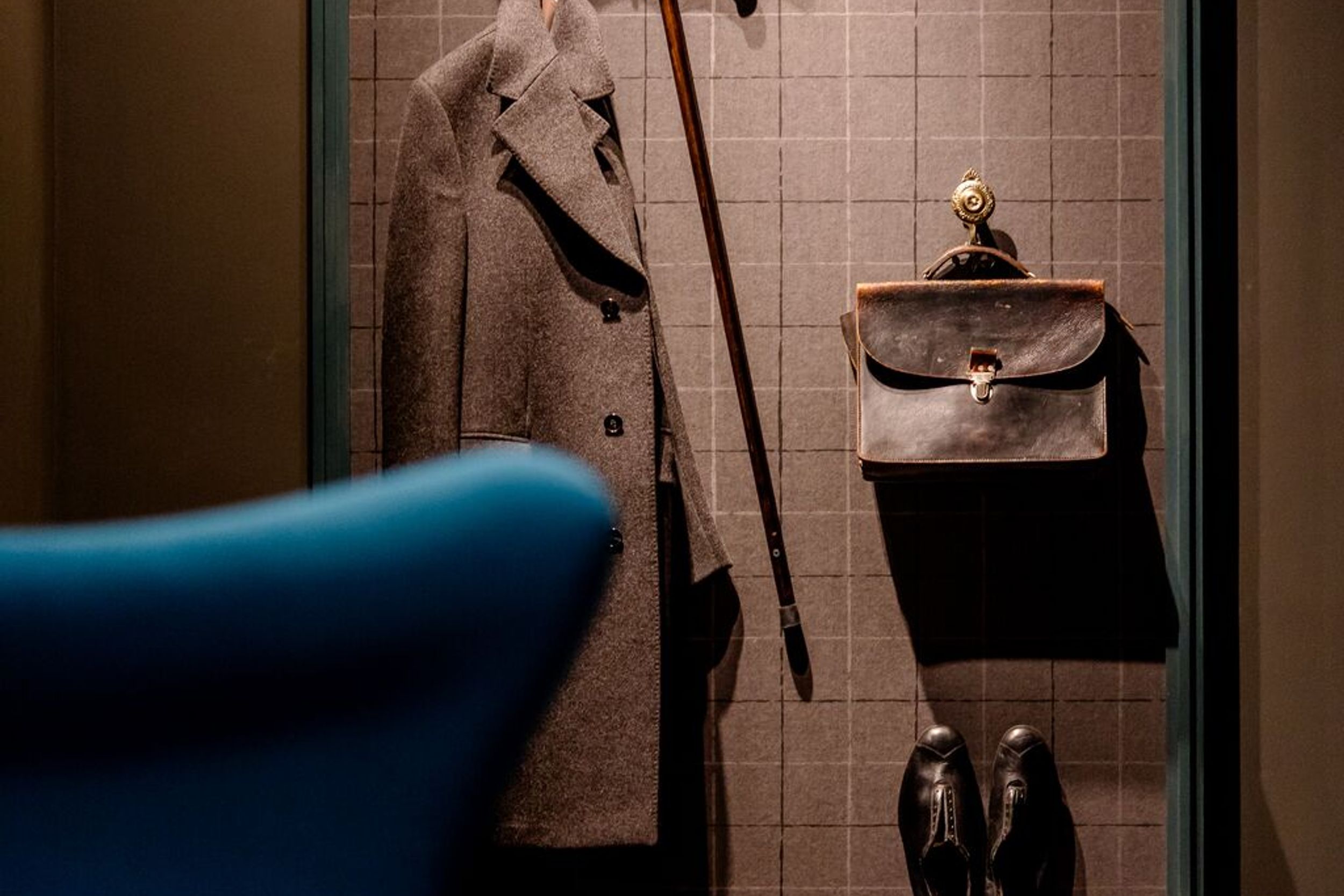 designhotel Dublin Motel One egg chair and coat rack with coat, cane, bag, hat, and shoes on the wall