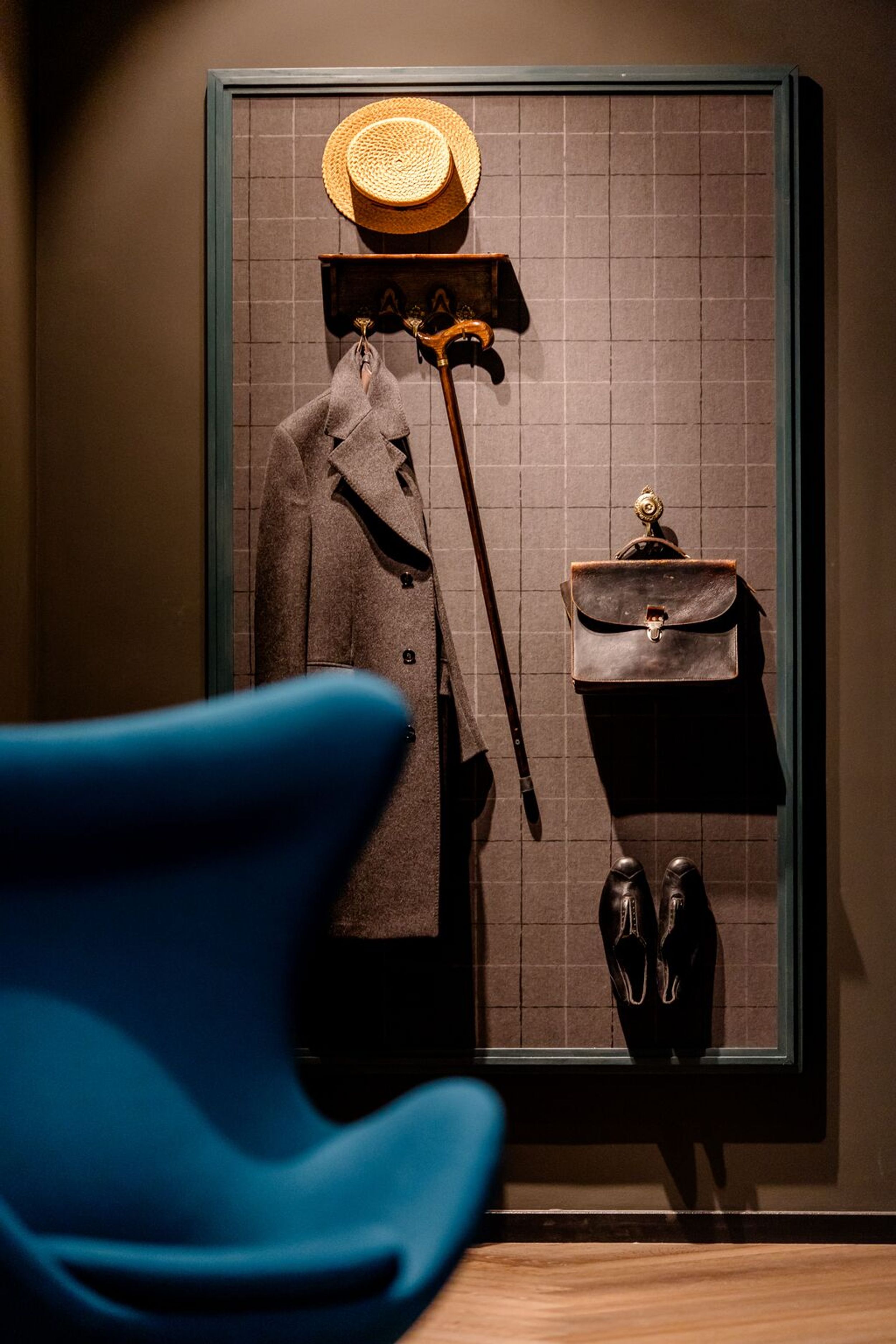 designhotel Dublin Motel One egg chair and coat rack with coat, cane, bag, hat, and shoes on the wall