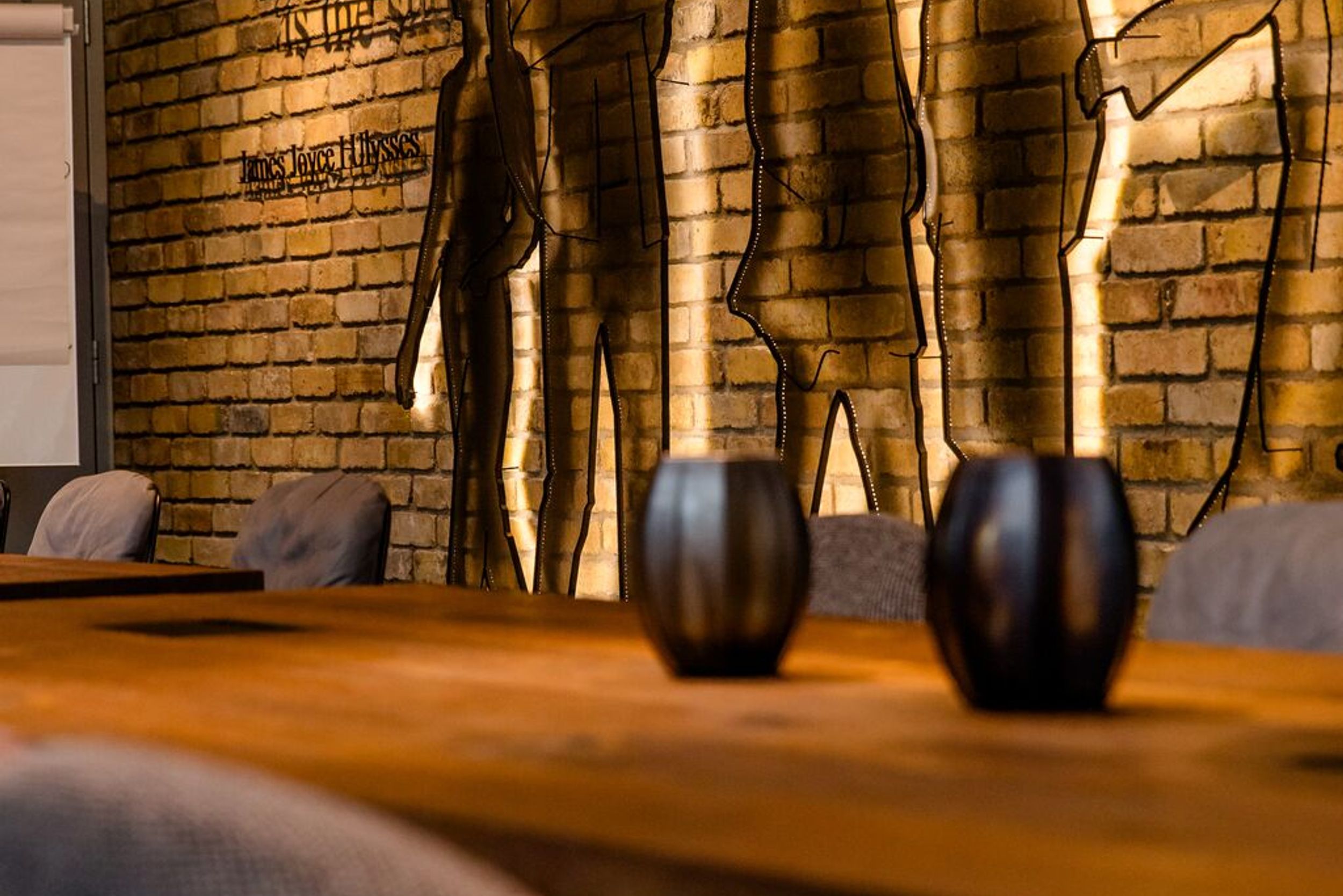 hotel Dublin Motel One long table with chairs in front of a wall installation featuring silhouettes of people and a quote from James Joyce