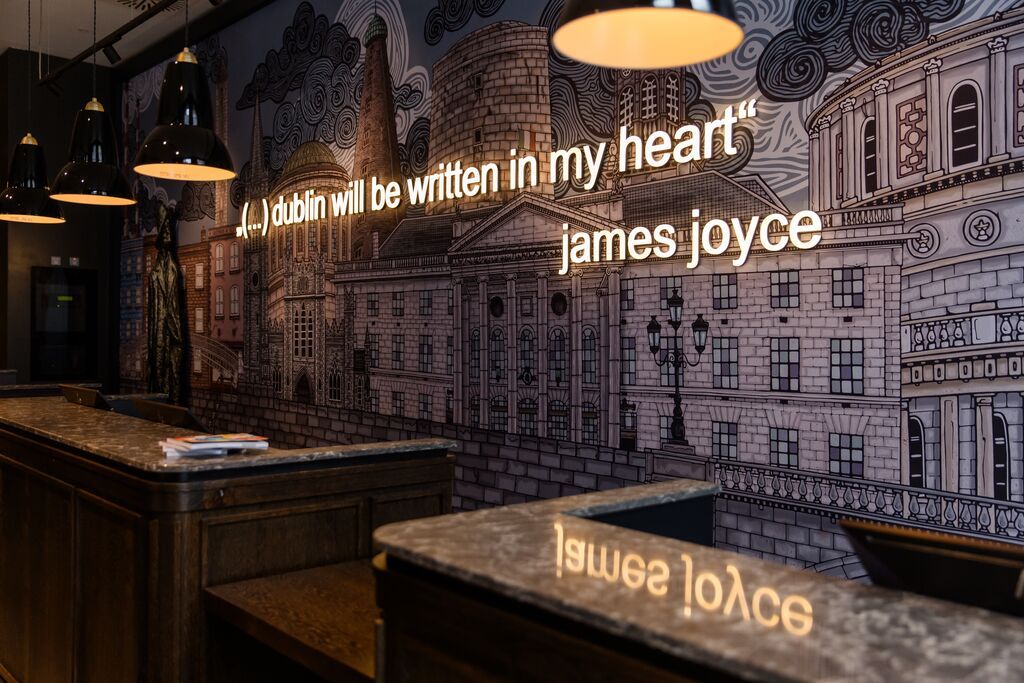 Designhotel Dublin Motel One Rezeption mit Zitat von James Joyce in Leuchtschrift an der Wand