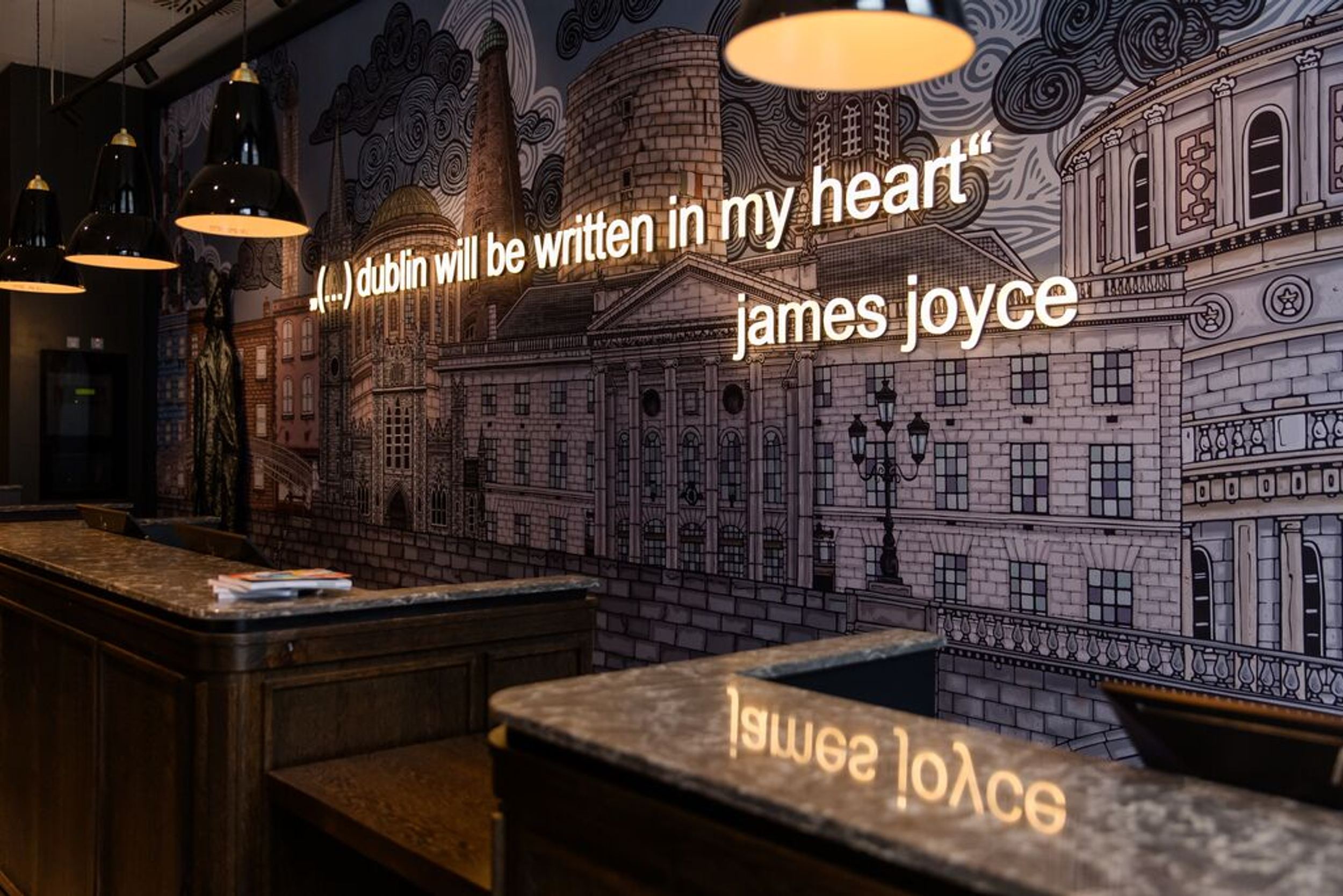 Designhotel Dublin Motel One Rezeption mit Zitat von James Joyce in Leuchtschrift an der Wand