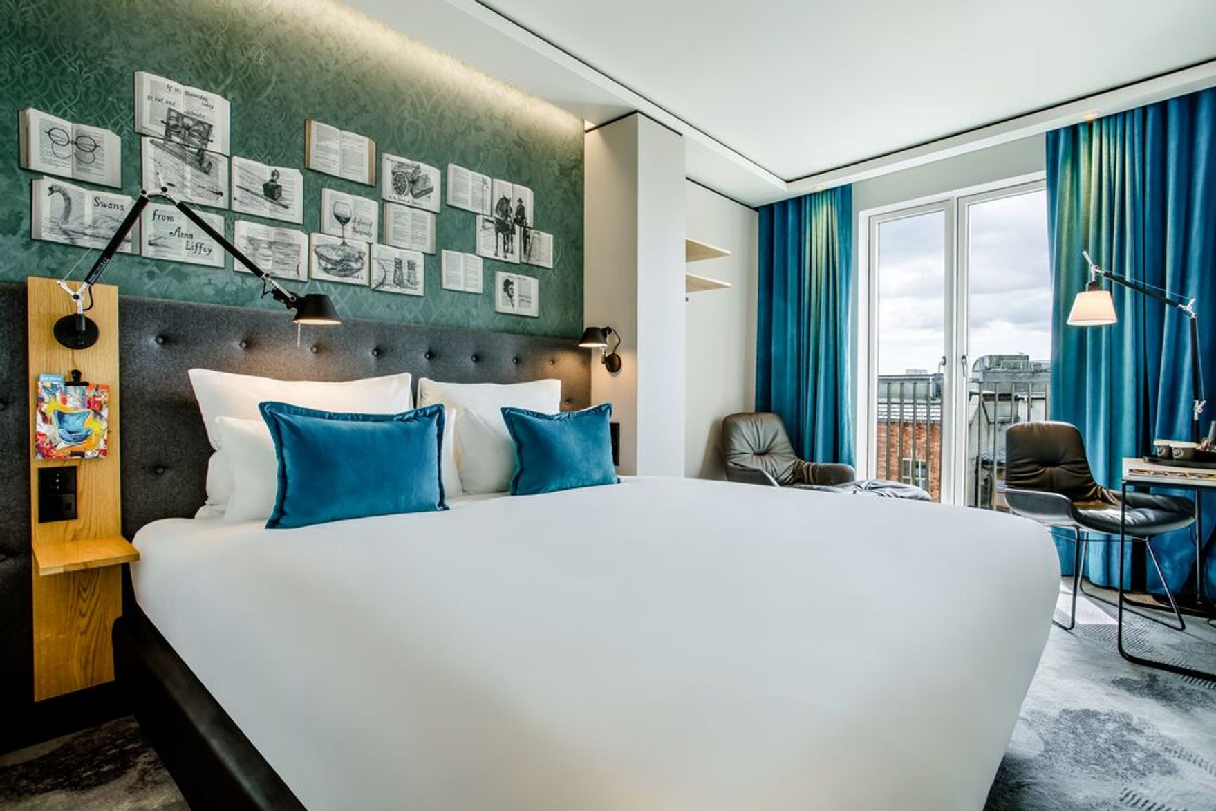 Hotel Dublin Motel One lichtdurchflutetes Zimmer mit großem Doppelbett und zwei Sesseln vor bodentiefem Fenster