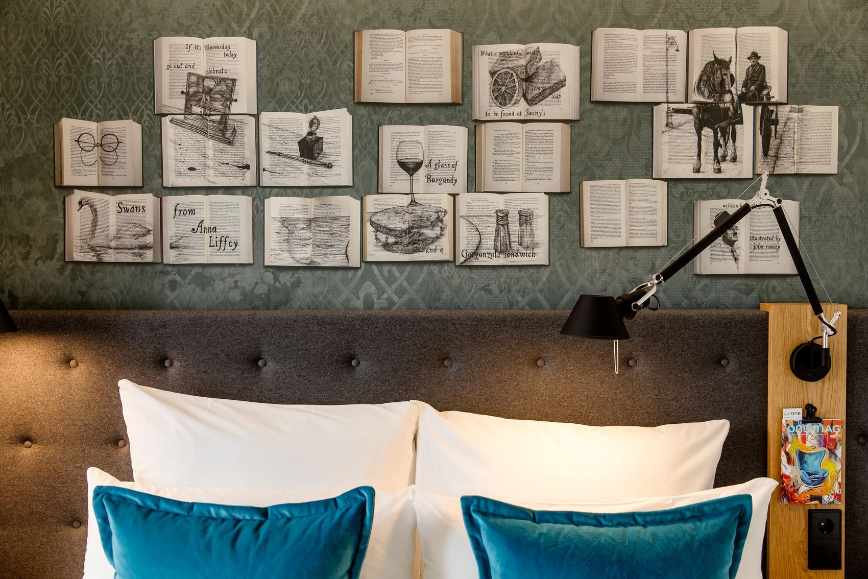 Hotel Dublin Motel One Zimmer mit Blick auf das Kopfteil eines Doppelbettes sowie Bücher an der Wand