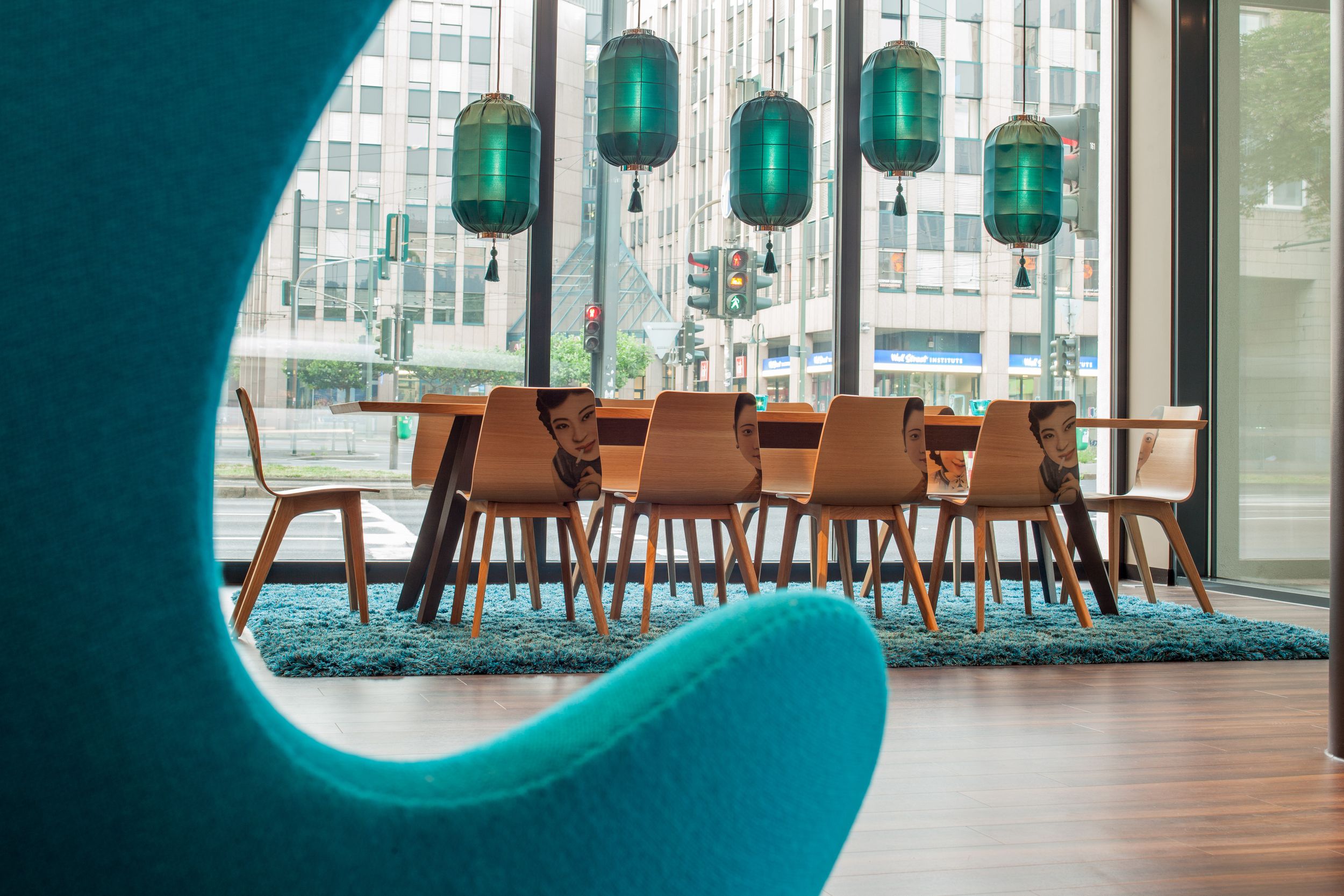 Hotel Düsseldorf Hauptbahnhof Motel One helle Lounge mit Blick über einen Egg Chair hin zu einem langen Tisch mit zehn Stühlen