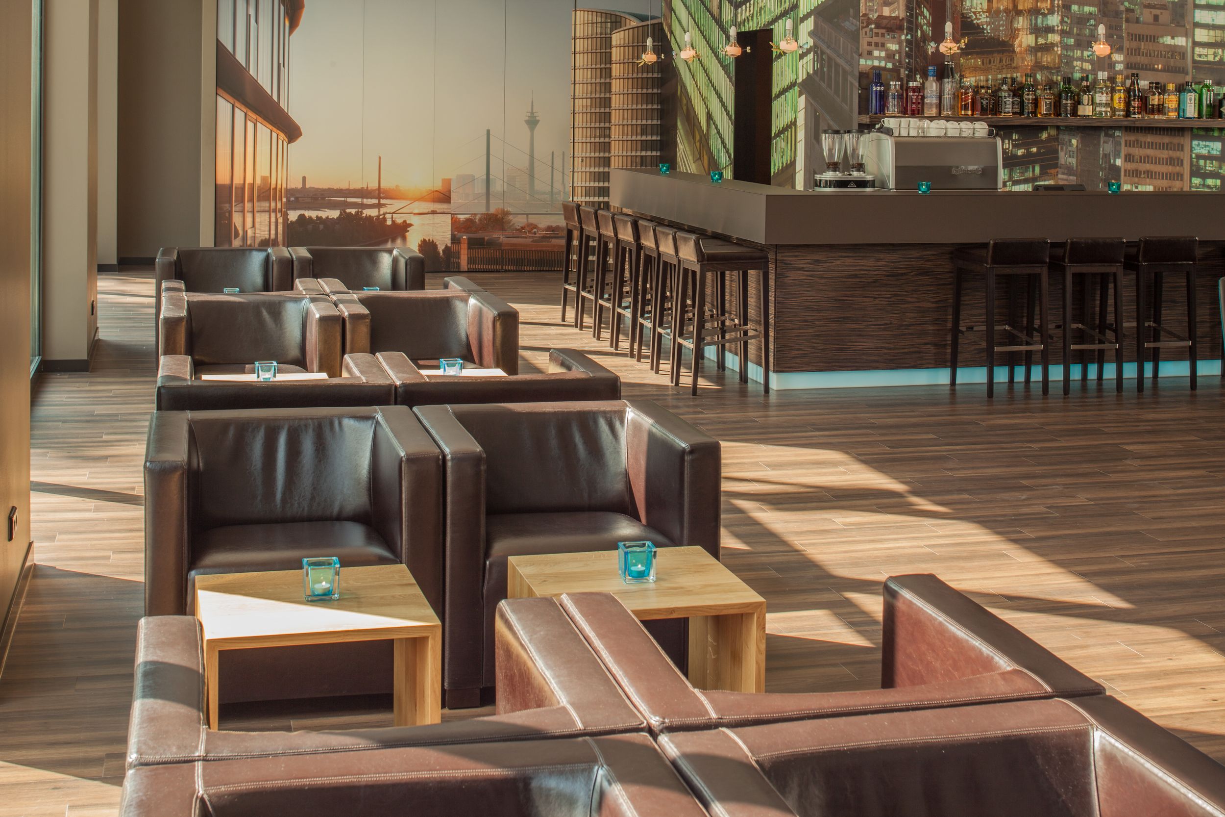 Hotel Düsseldorf Hauptbahnhof Motel One Lounge mit Sonneneinstrahlung und mehreren Sesseln sowie die Bar im Hintergrund