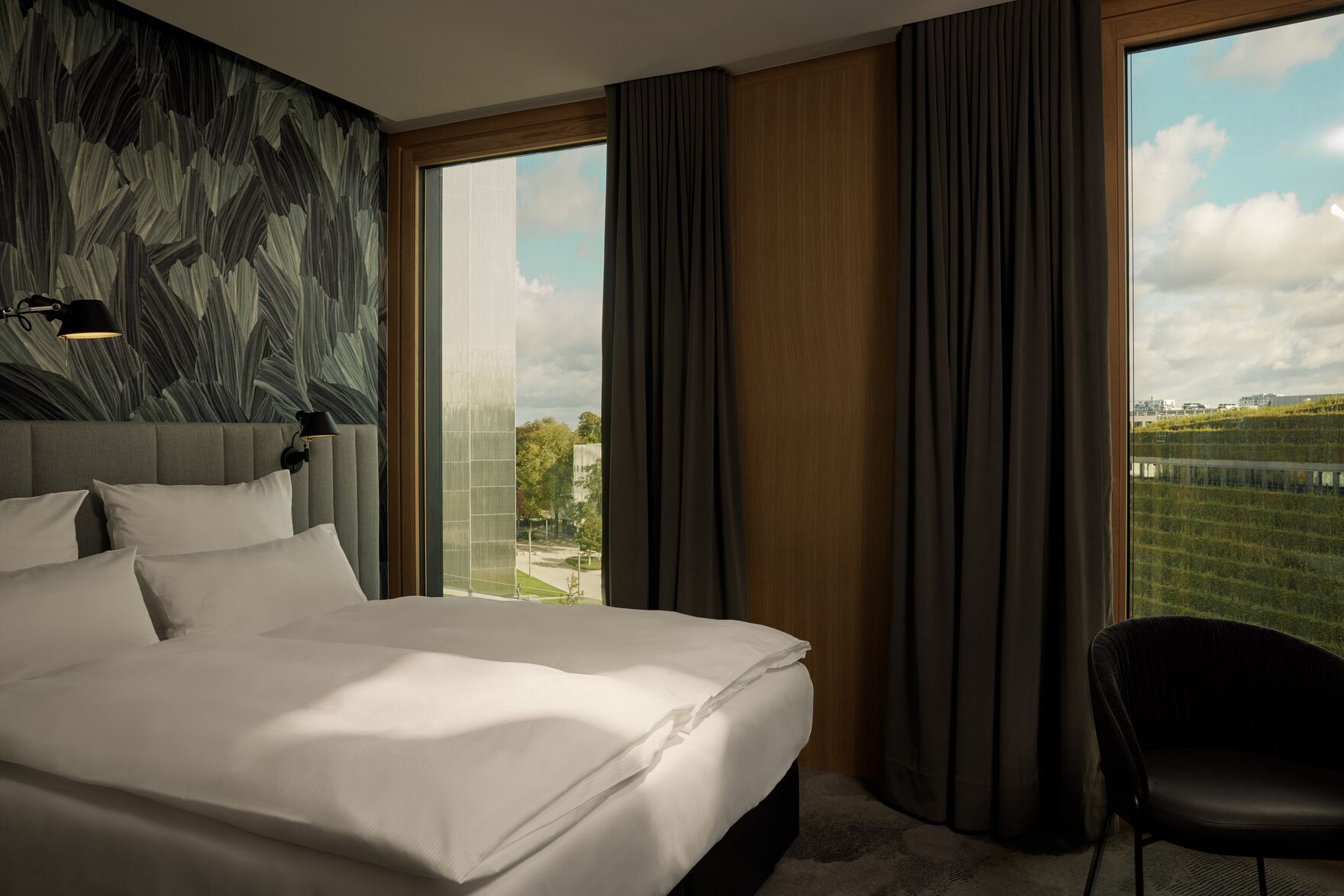 Designhotel Düsseldorf KöBogen The Cloud One helles Zimmer mit Doppelbett und zwei bodentiefen Fenstern und Sessel