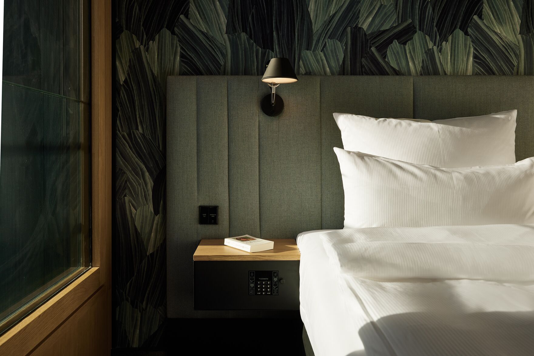 Designhotel Düsseldorf KöBogen The Cloud One lichtdurchflutetes Zimmer mit Bett und Nachttisch mit Safe