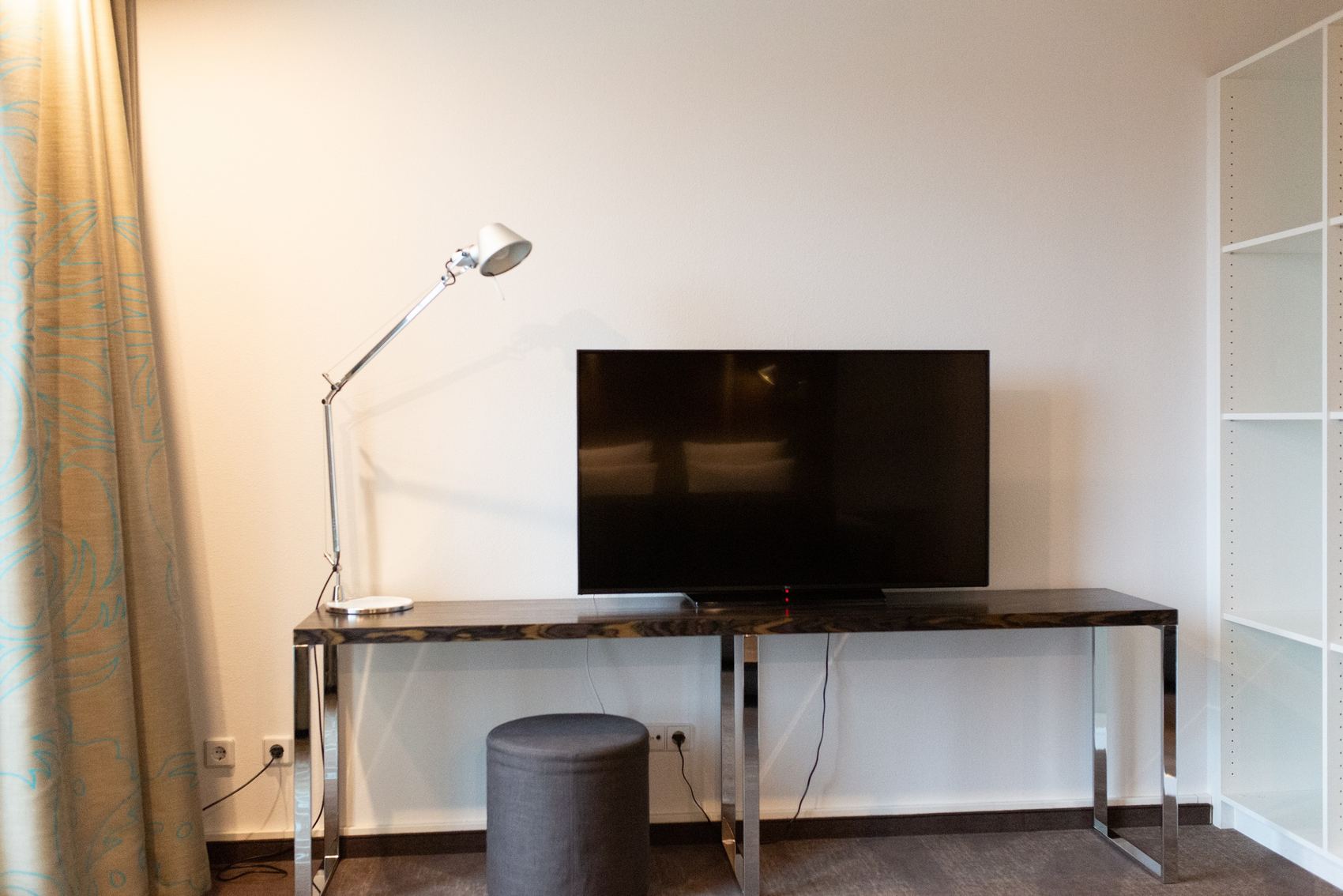 Hotel Düsseldorf Hauptbahnhof Motel One helles Zimmer mit Blick auf breiten Tisch mit einem großen Fernseher in der Mitte