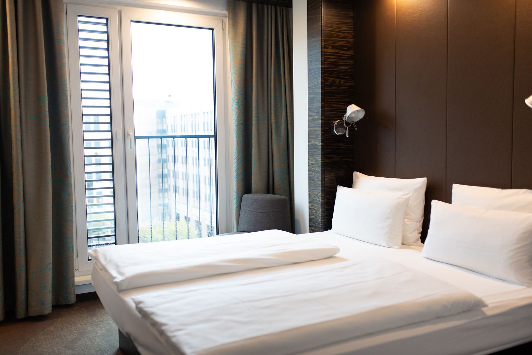 Hotel Düsseldorf Hauptbahnhof Motel One seitlicher Blick in helles Zimmer mit großem Doppelbett und bodentiefem Fenster