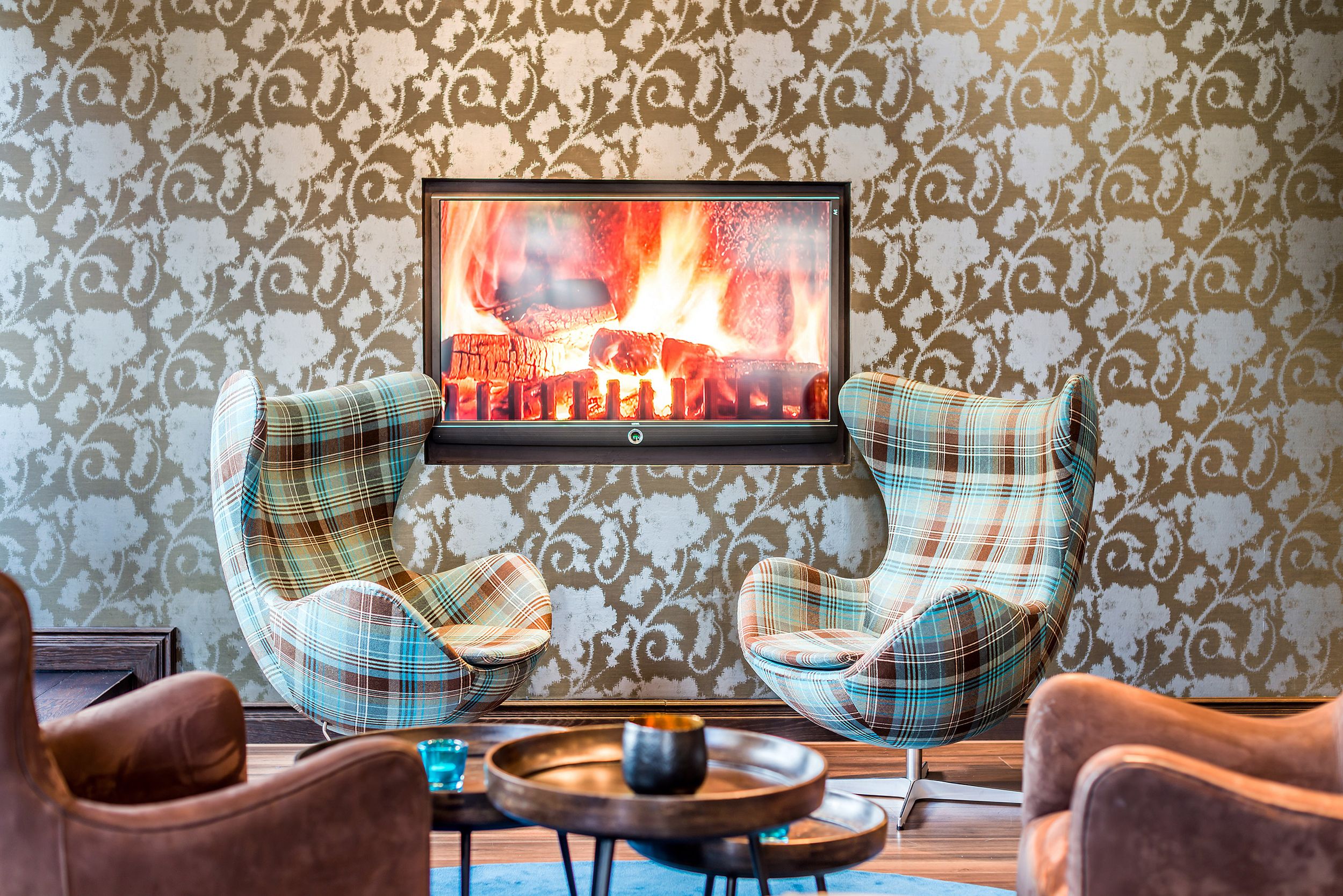 Designhotel Edinburgh Princes Motel One zwei Egg Chairs mit Schottenkaro-Muster sowie Fernseher mit Feuermotiv an der Wand