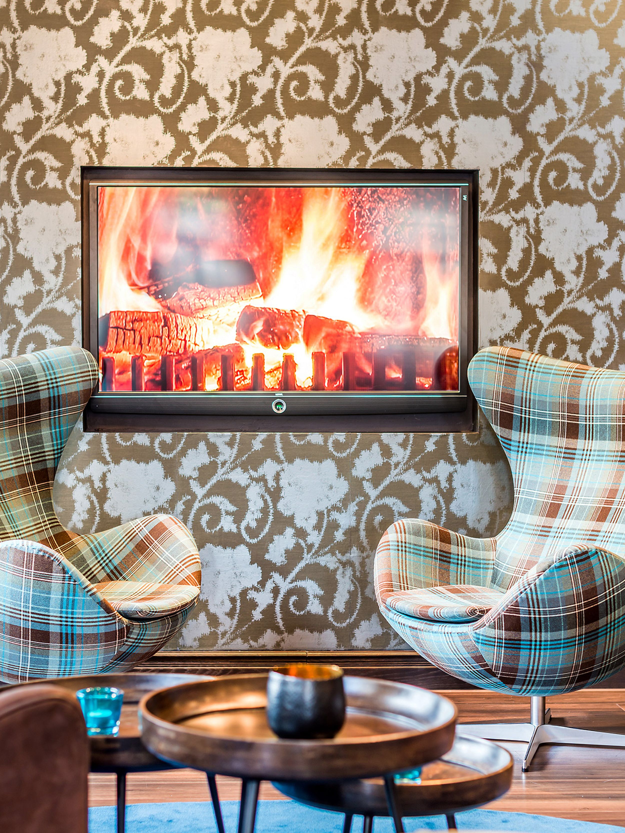 Designhotel Edinburgh Princes Motel One zwei Egg Chairs mit Schottenkaro-Muster sowie Fernseher mit Feuermotiv an der Wand
