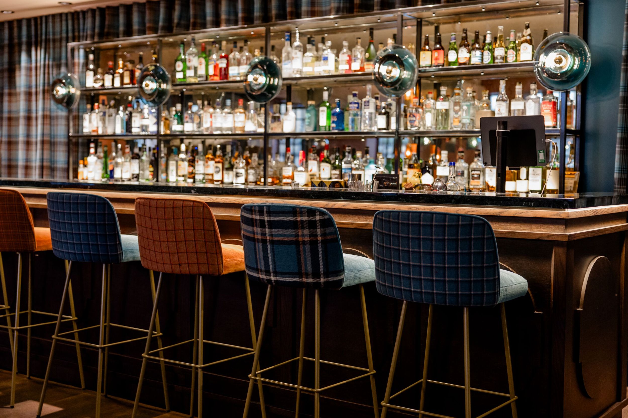 Hotel Edinburgh Princes Motel One Bar mit langer Theke und Barhockern sowie ein großes Regal mit Spirituosen