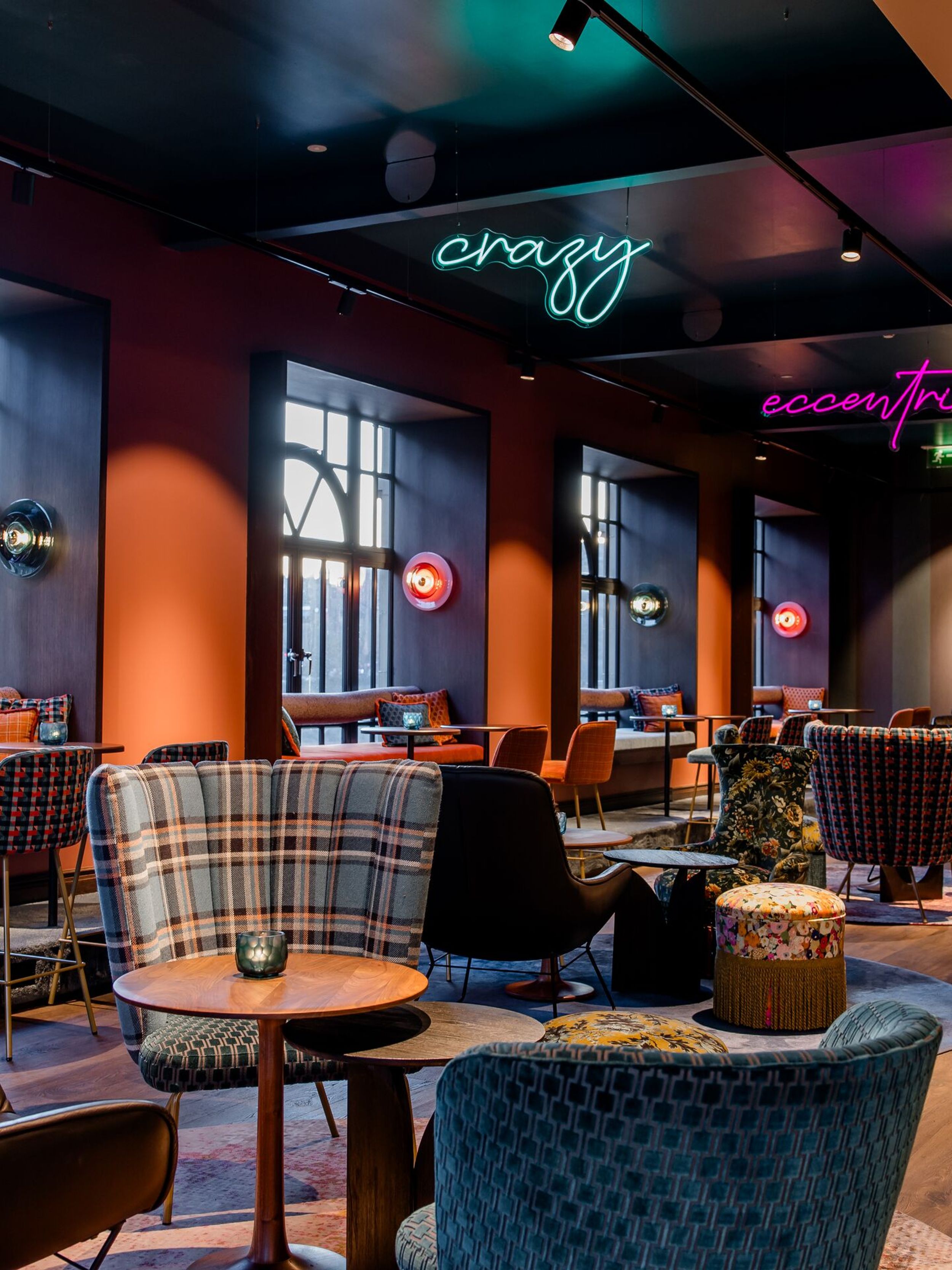 Hotel Edinburgh Princes Motel One große Lounge mit mehreren Sitzgelegenheiten sowie drei Neonschilder in unterschiedlichen Farben, die von der Decke hängen