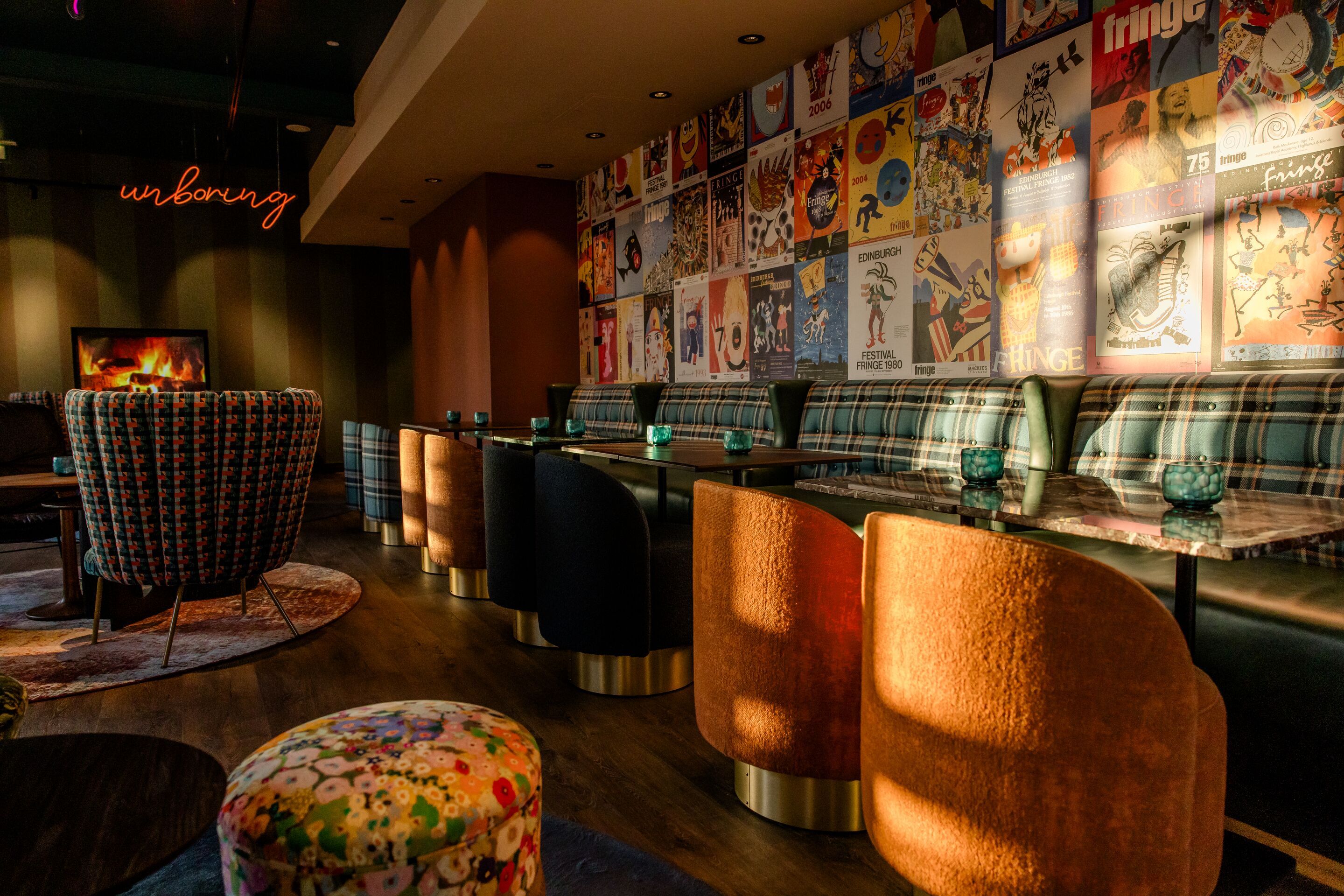 Hotel Edinburgh Princes Motel One lichtdurchflutete Lounge mit mehreren Tischen, Stühlen und Sesseln sowie ein Neonschild mit der Aufschrift unboring