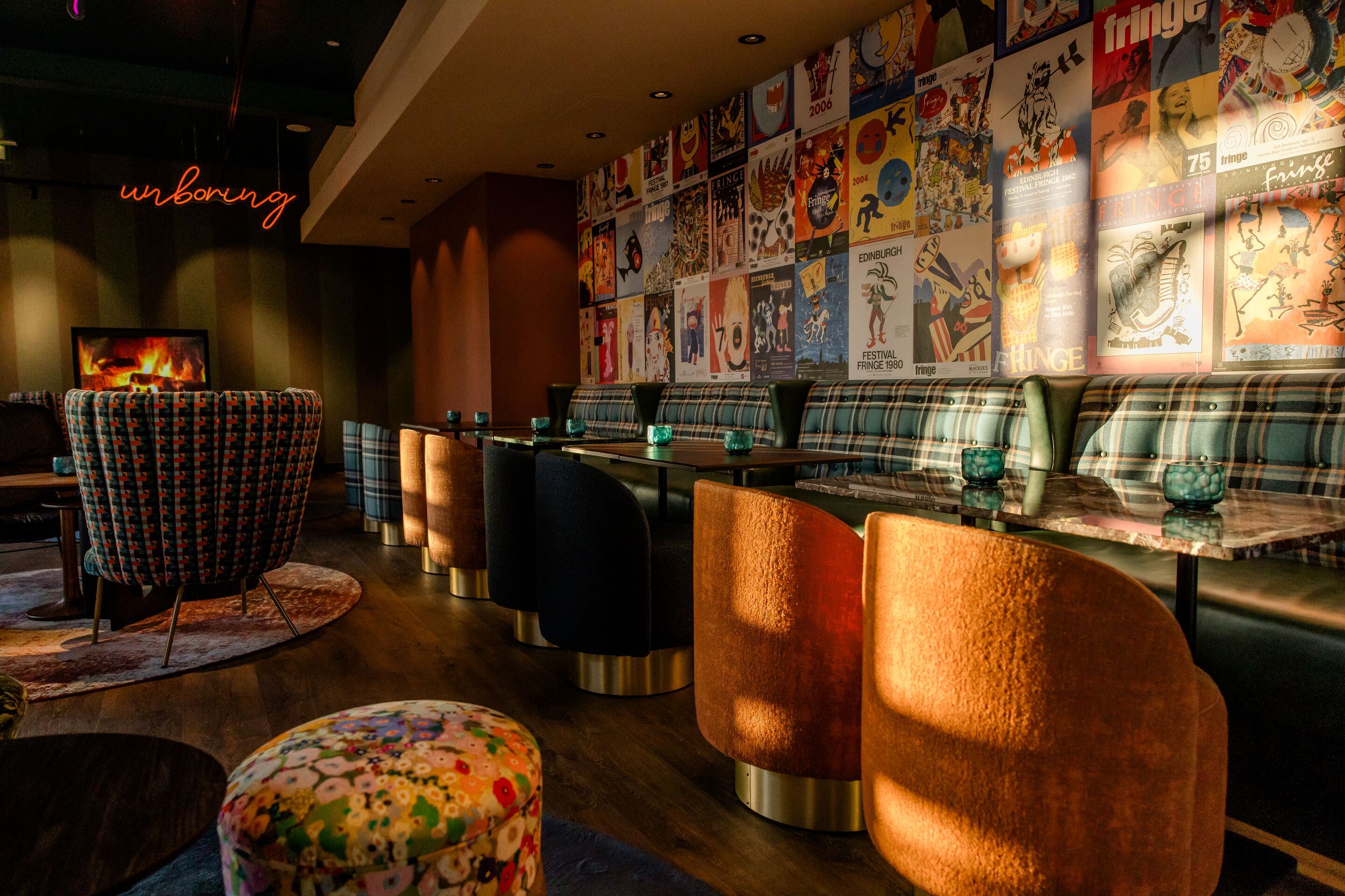 Hotel Edinburgh Princes Motel One lichtdurchflutete Lounge mit mehreren Tischen, Stühlen und Sesseln sowie ein Neonschild mit der Aufschrift unboring Hotel Edinburgh Princes Motel One lichtdurchflutete Lounge mit mehreren Tischen, Stühlen und Sesseln sowie ein Neonschild mit der Aufschrift unboring