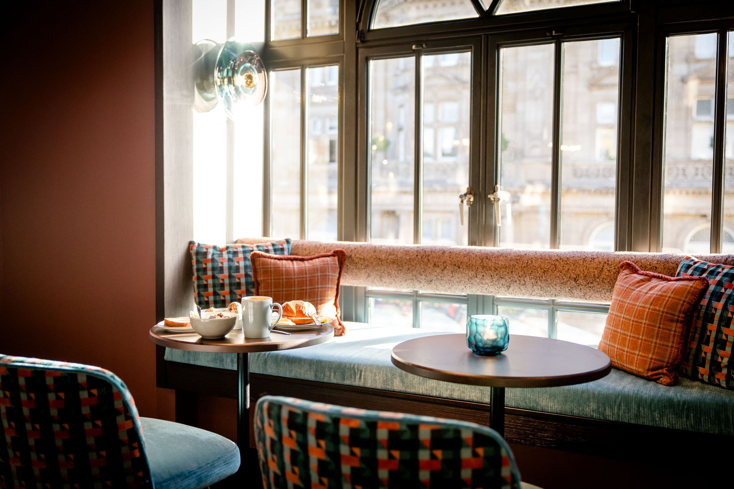 Hotel Edinburgh Princes Motel One Sitzbank an einem großen Fenster sowie Sessel um einen gedeckten Frühstückstisch