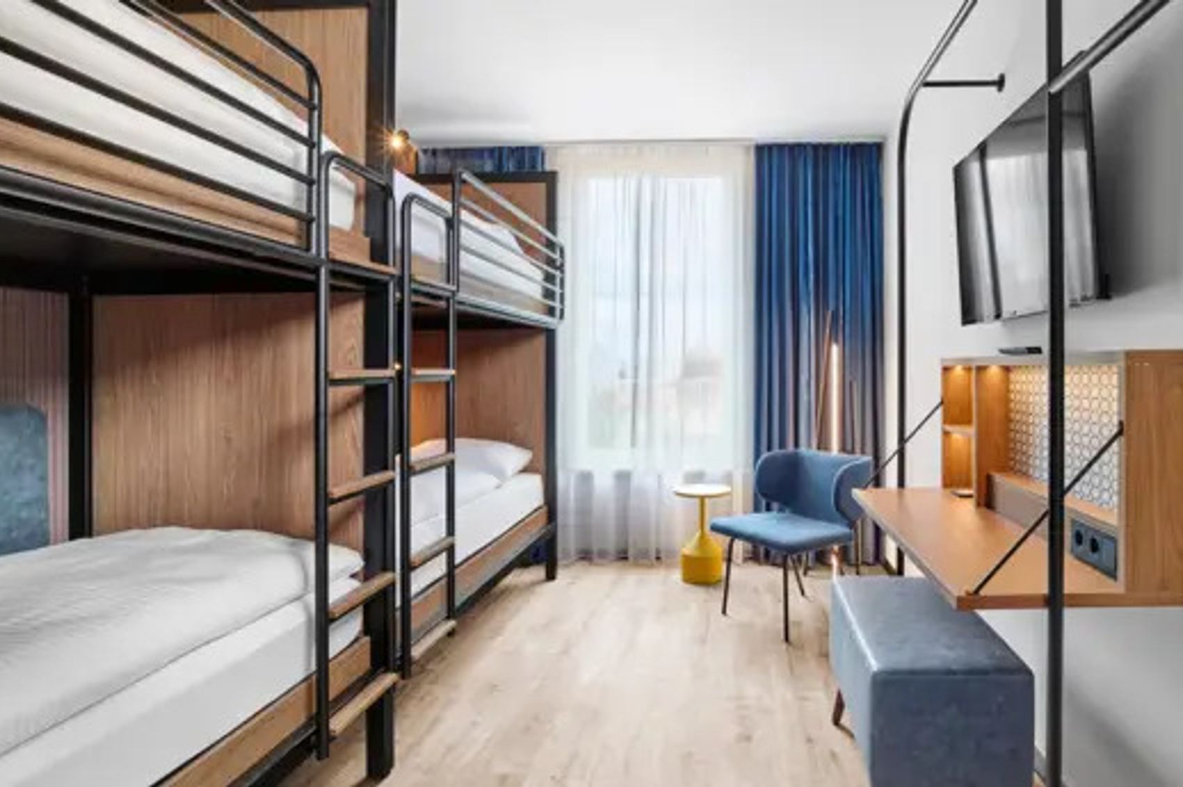 Hotel Erfurt-City Modernes Zimmer mit zwei Etagenbetten, großem Fenster, Schreibtisch, gemütlichem Stuhl und TV, hell und funktional gestaltet, ideal für Familien oder Gruppenreisende.