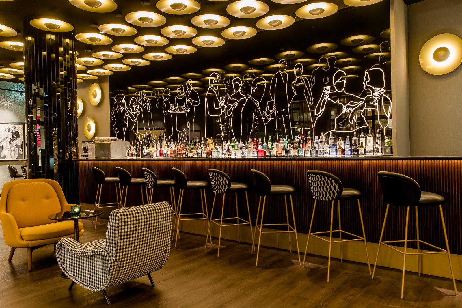 Hotel Essen Motel One Bar mit Sitzgelegenheiten und schwarze Rückwand mit leuchtenden Umrissen von Personen