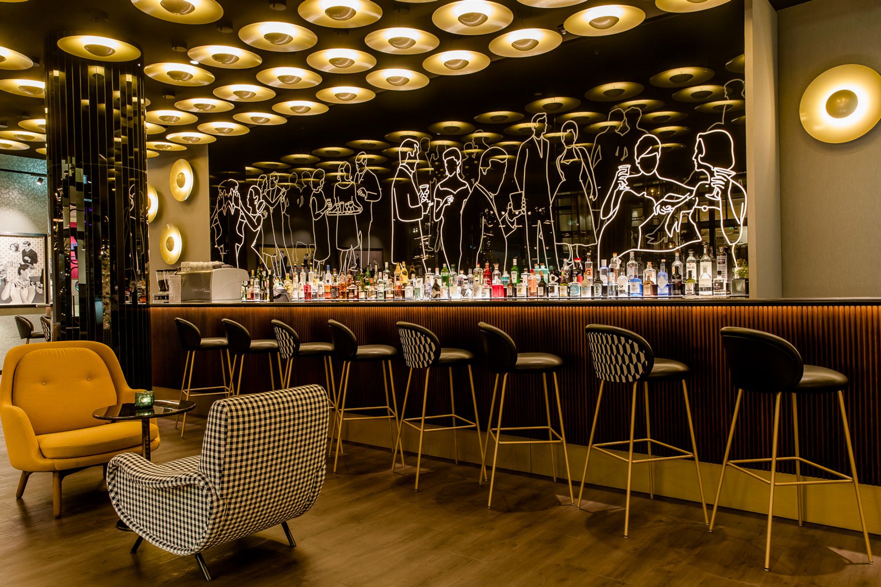 Hotel Essen Motel One Bar mit Sitzgelegenheiten und schwarze Rückwand mit leuchtenden Umrissen von Personen