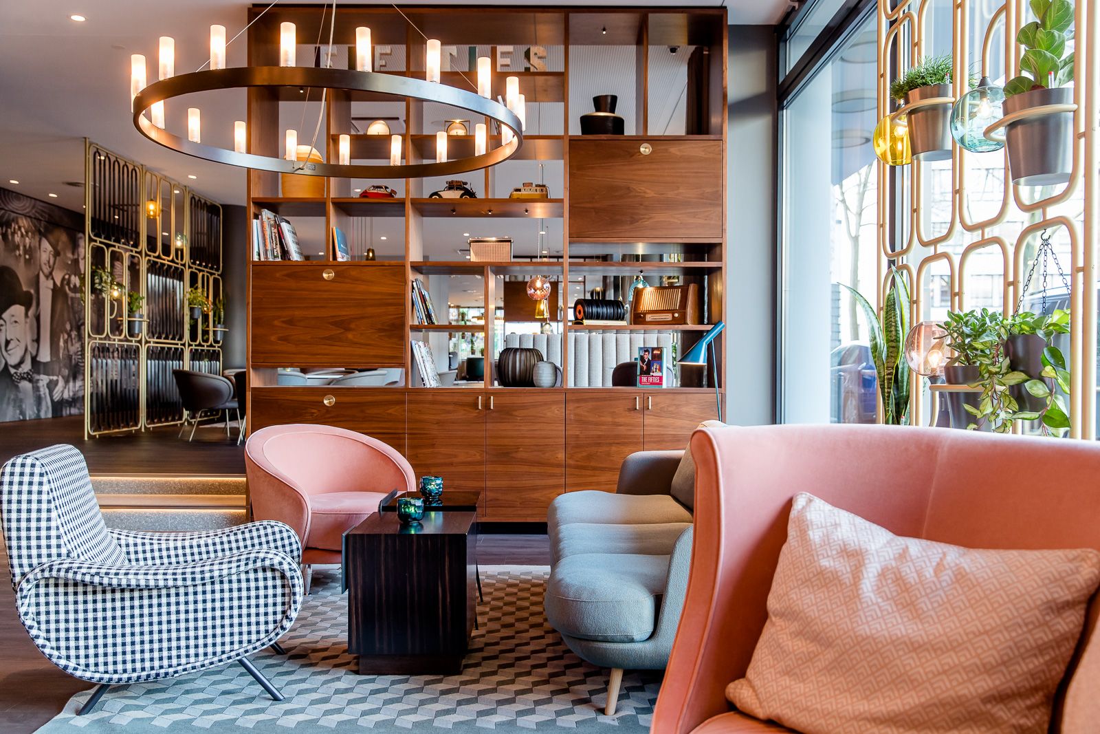 Designhotel Essen Motel One lichtdurchflutete Lounge mit mehreren Sesseln und großem offenen Regal aus Holz