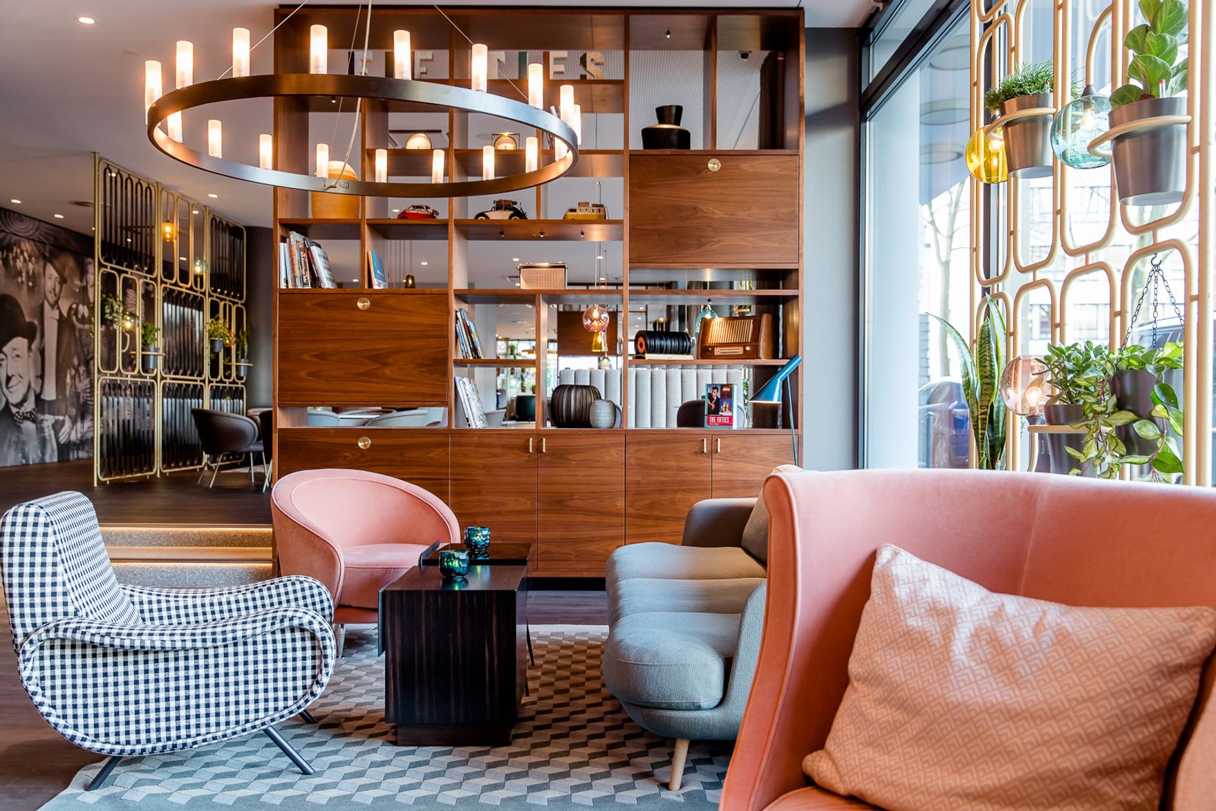 Designhotel Essen Motel One lichtdurchflutete Lounge mit mehreren Sesseln und großem offenen Regal aus Holz