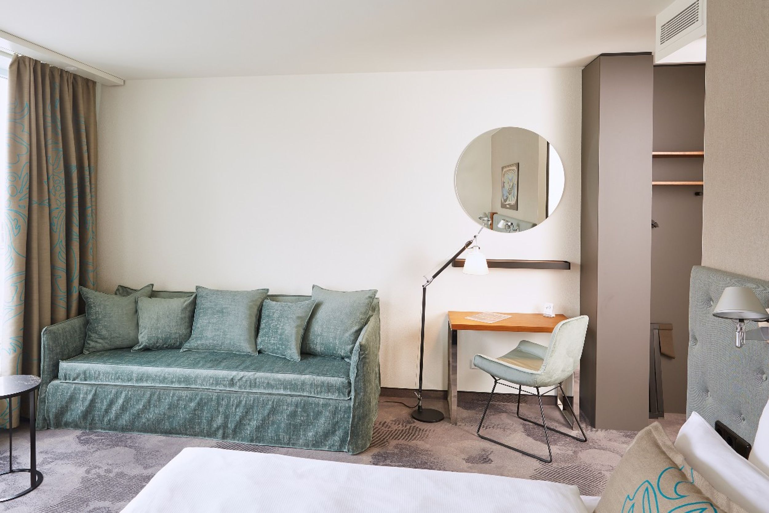 hotel Essen Motel One bright room with a view of a large couch, bed, desk and chair