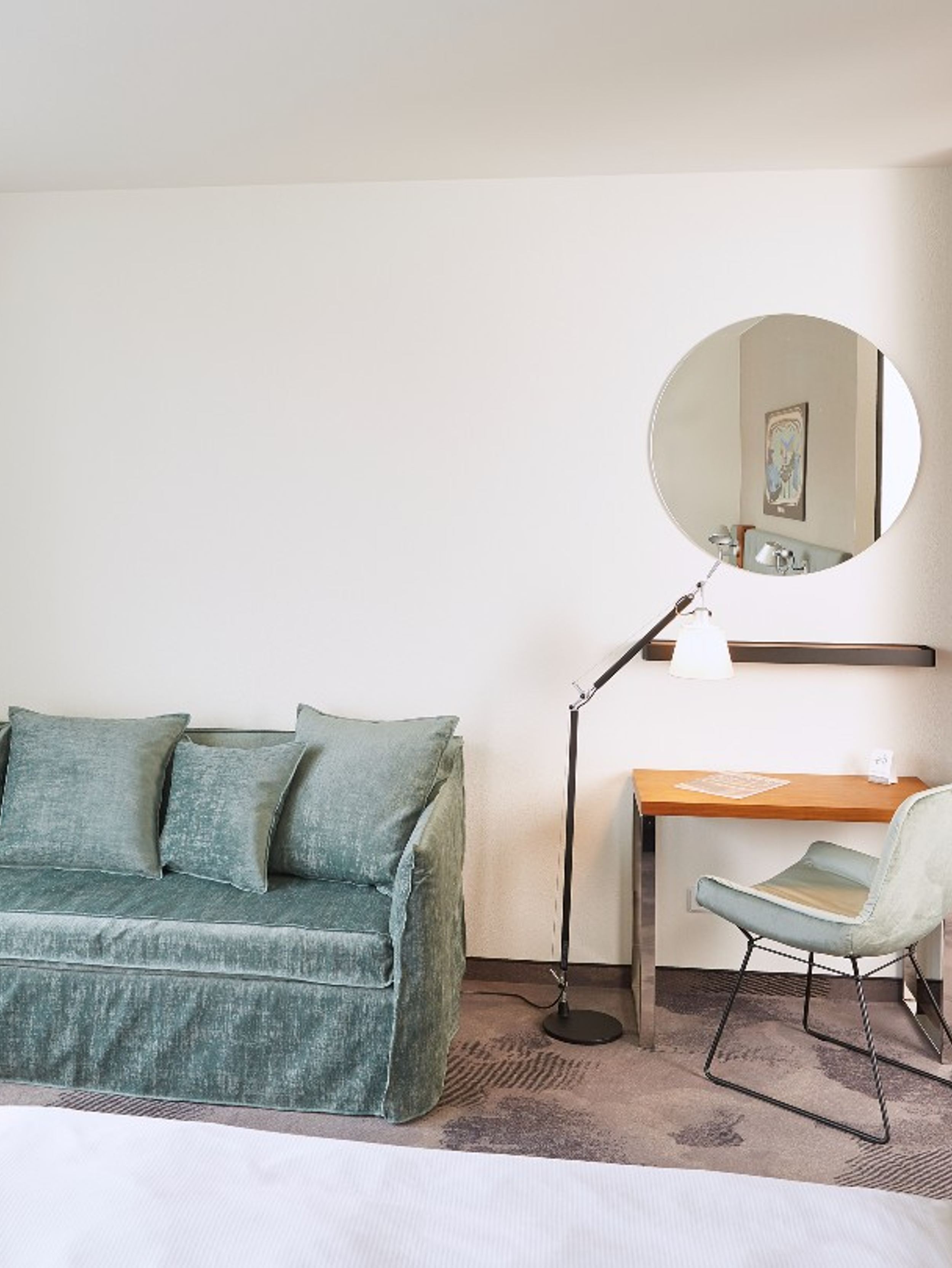 Hotel Essen Motel One helles Zimmer mit Blick auf eine große Couch, Bett, Schreibtisch und Stuhl