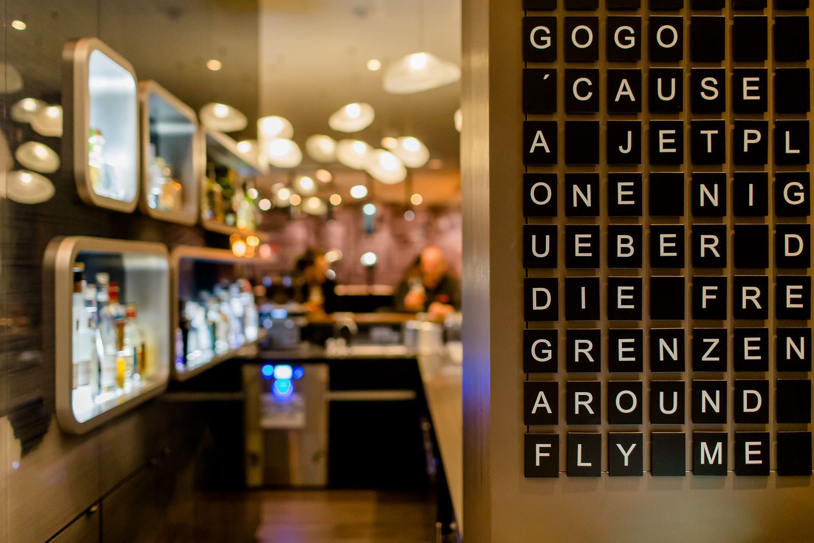 Hotel Frankfurt Airport Motel One Blick auf eine Anzeigetafel in der Lounge, im Hintergrund die Bar