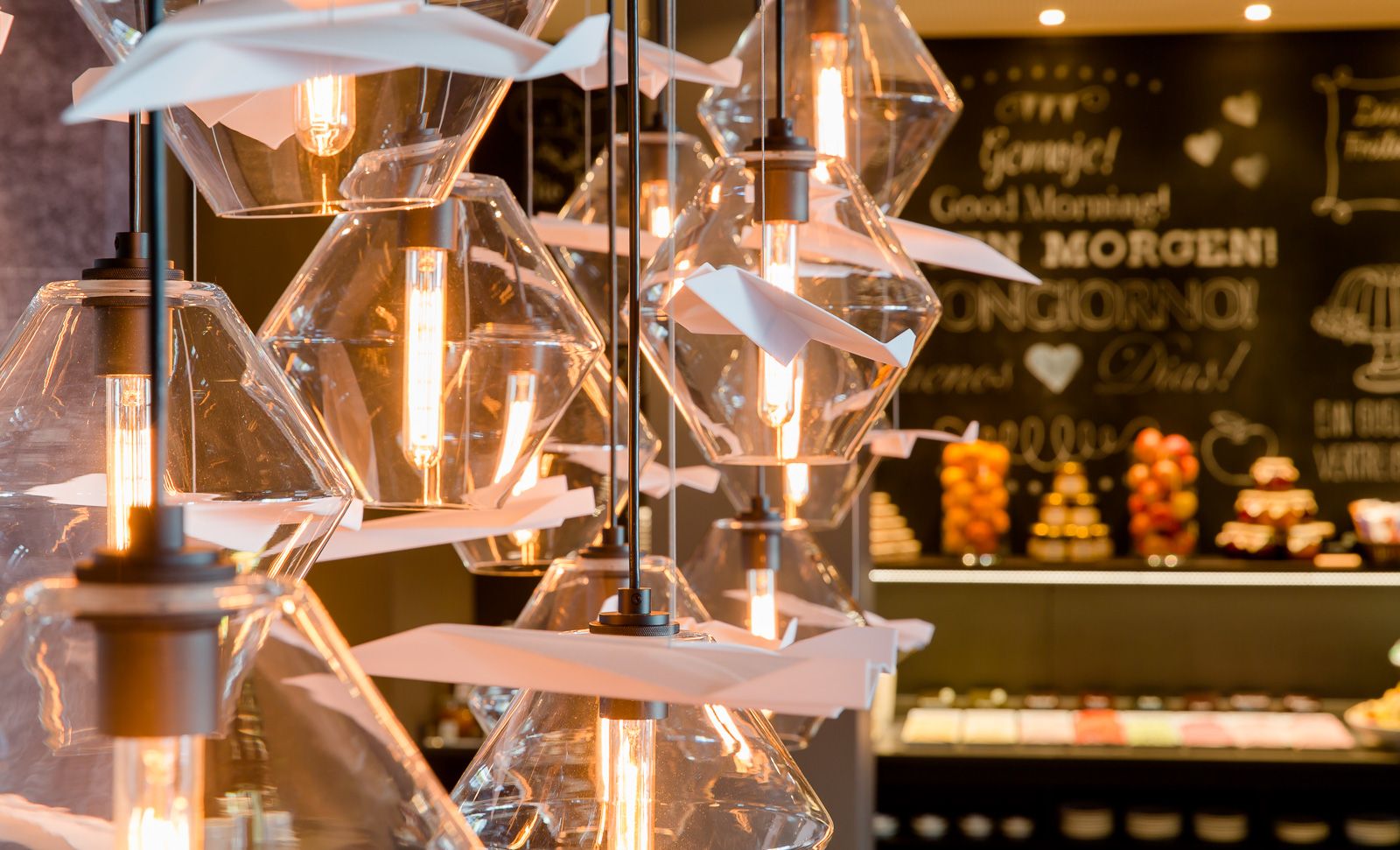 Hotel Frankfurt Airport Motel One Nahaufnahme auf Lampen in Frühstücksraum mit Buffet im Hintergrund