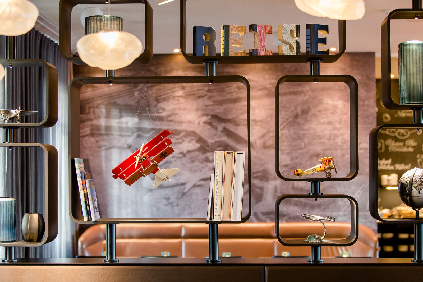 Designhotel Frankfurt Airport Motel One offenes Regal mit Schriftzug Reise und weiterer themenbezogener Dekoration