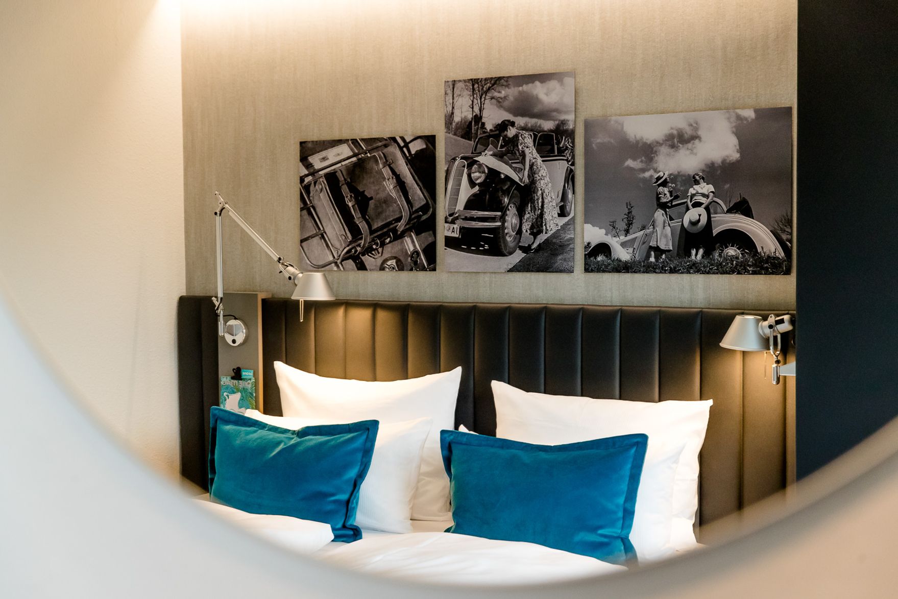 Hotel Frankfurt East Side Motel One Blick durch runden Spiegel auf ein großes Doppelbett mit zwei Zierkissen