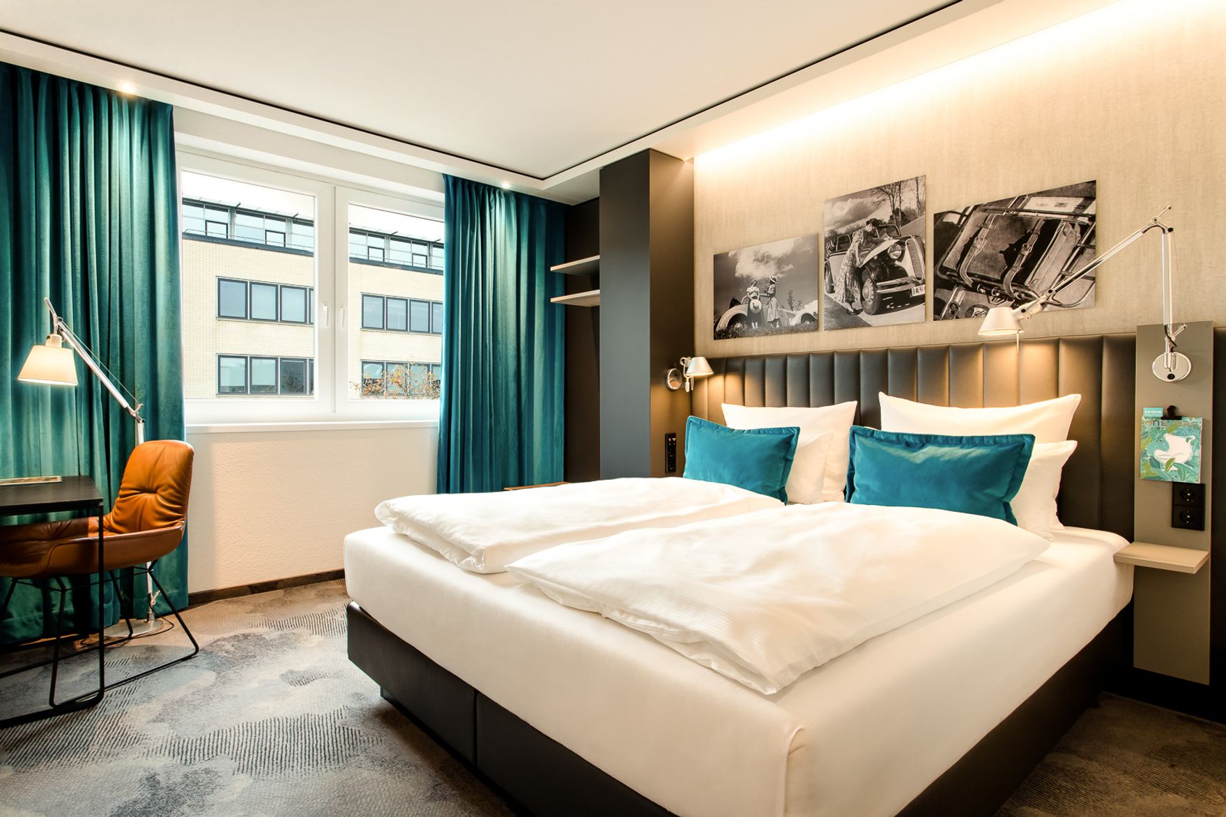 Hotel Frankfurt East Side Motel One lichtdurchflutetes Zimmer mit Doppelbett sowie Schreibtisch mit Stuhl