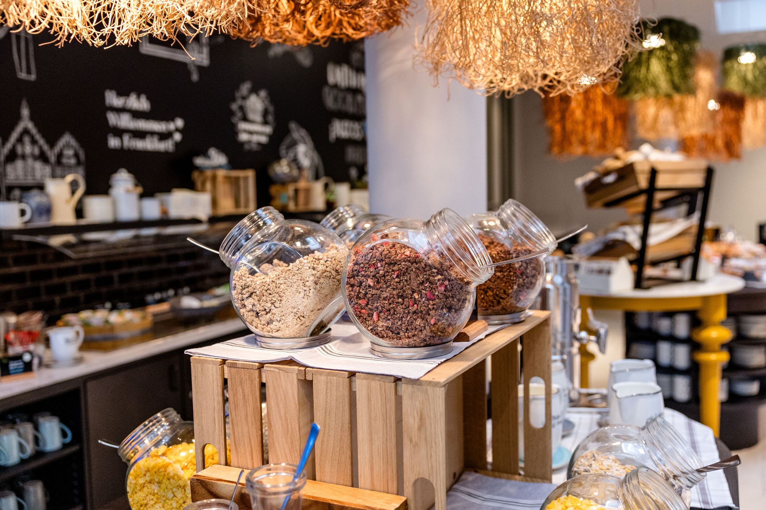 Hotel Frankfurt-Hauptbahnhof Motel One Frühstücksbuffet mit Müsli und Cerealien in Glasbehältern auf Holzkisten dekorativ präsentiert.